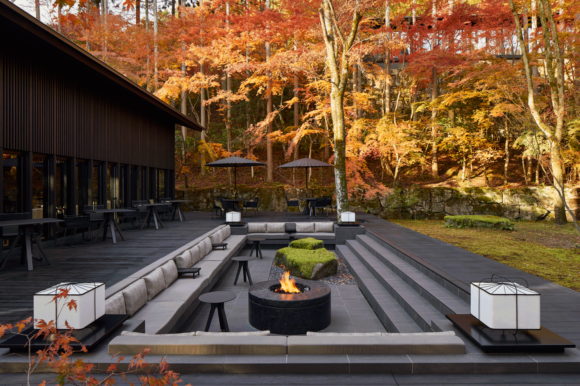 Contemporary outdoor terrace at Aman Kyoto with fire pit seating surrounded by vibrant autumn foliage.