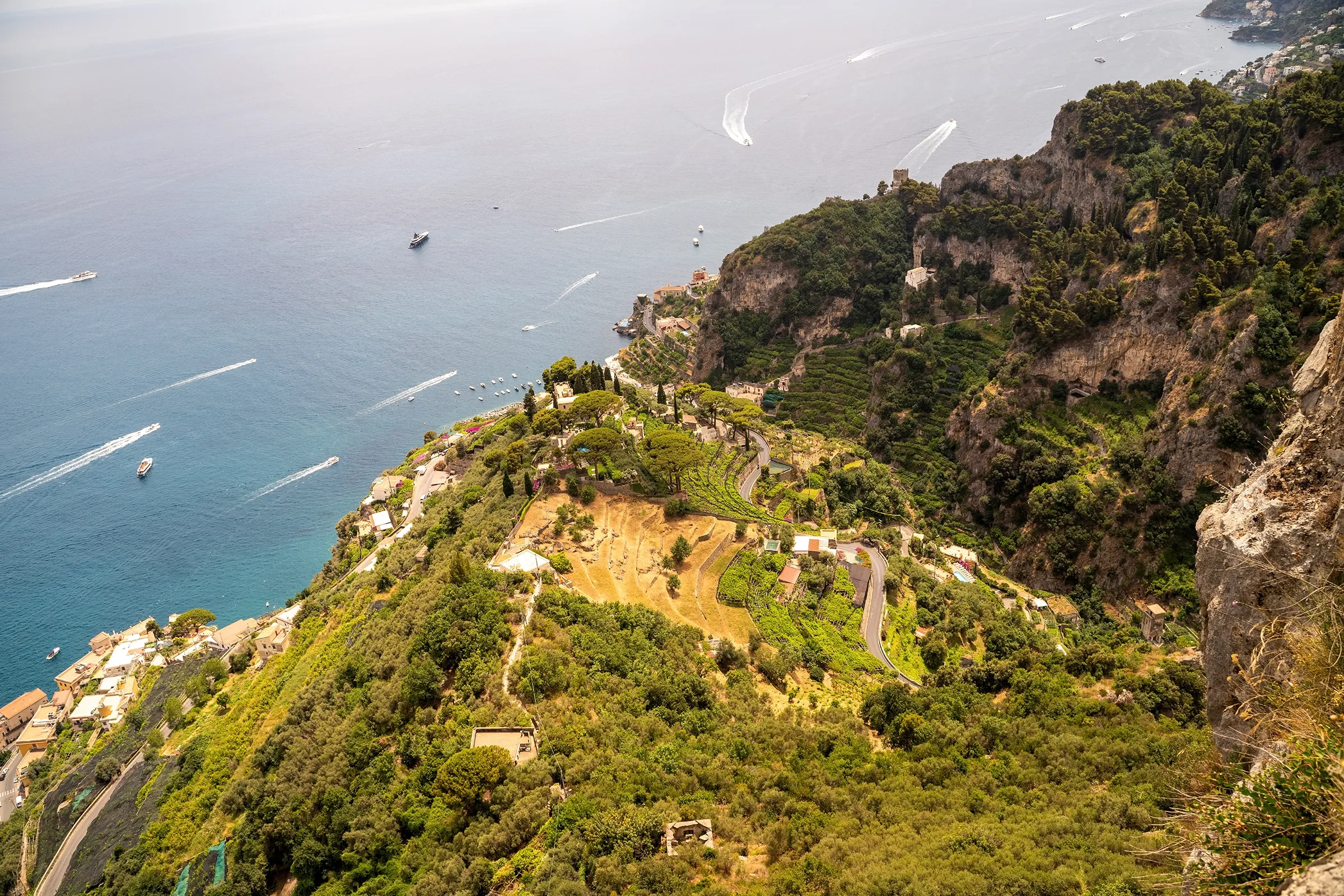 Aerial view of the terraced hills and coastal cliffs of Valle delle Ferriere Nature Reserve overlooking the blue waters of the Amalfi Coast in Italy.