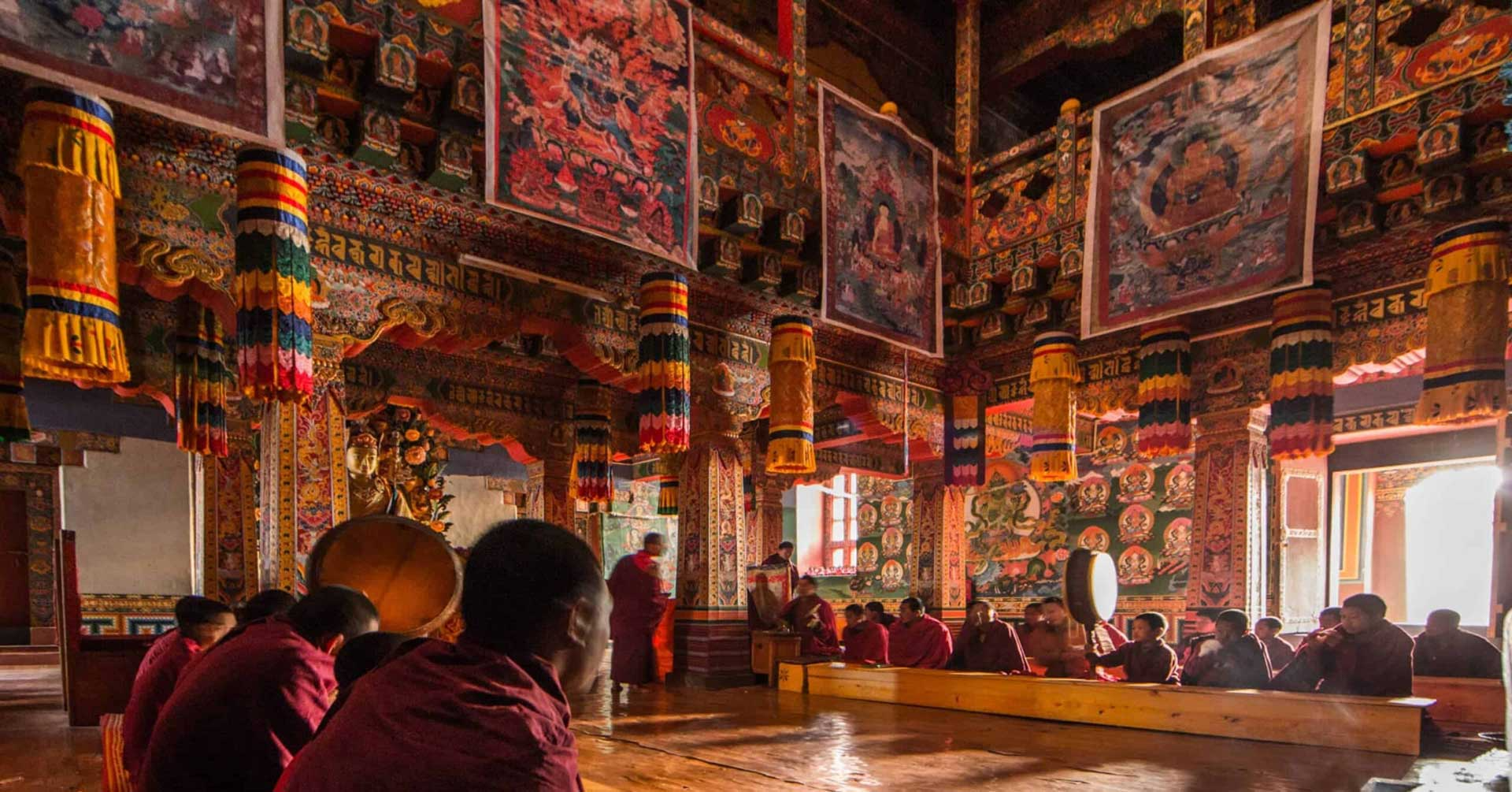 Monks gathered inside a richly decorated temple hall, seated as part of a traditional ceremony.