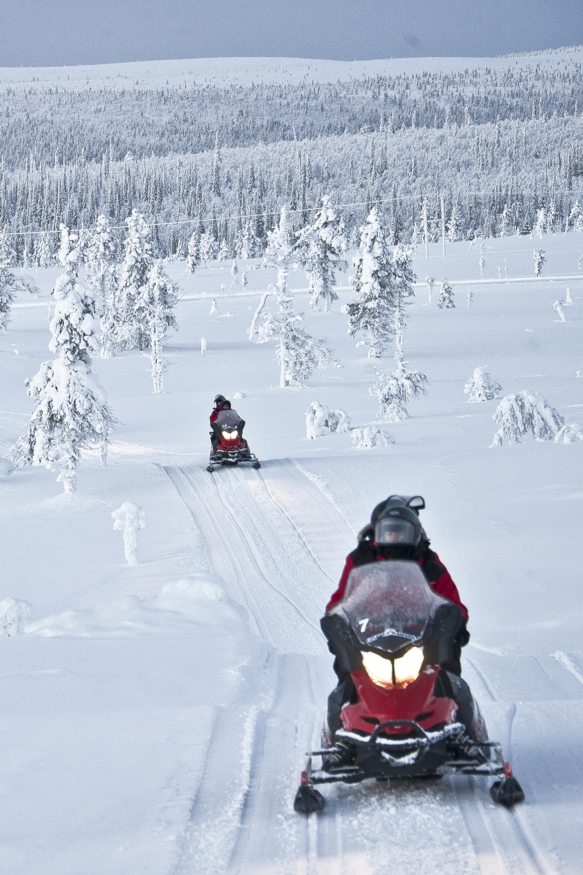 People on snowmobiles riding through the landscape