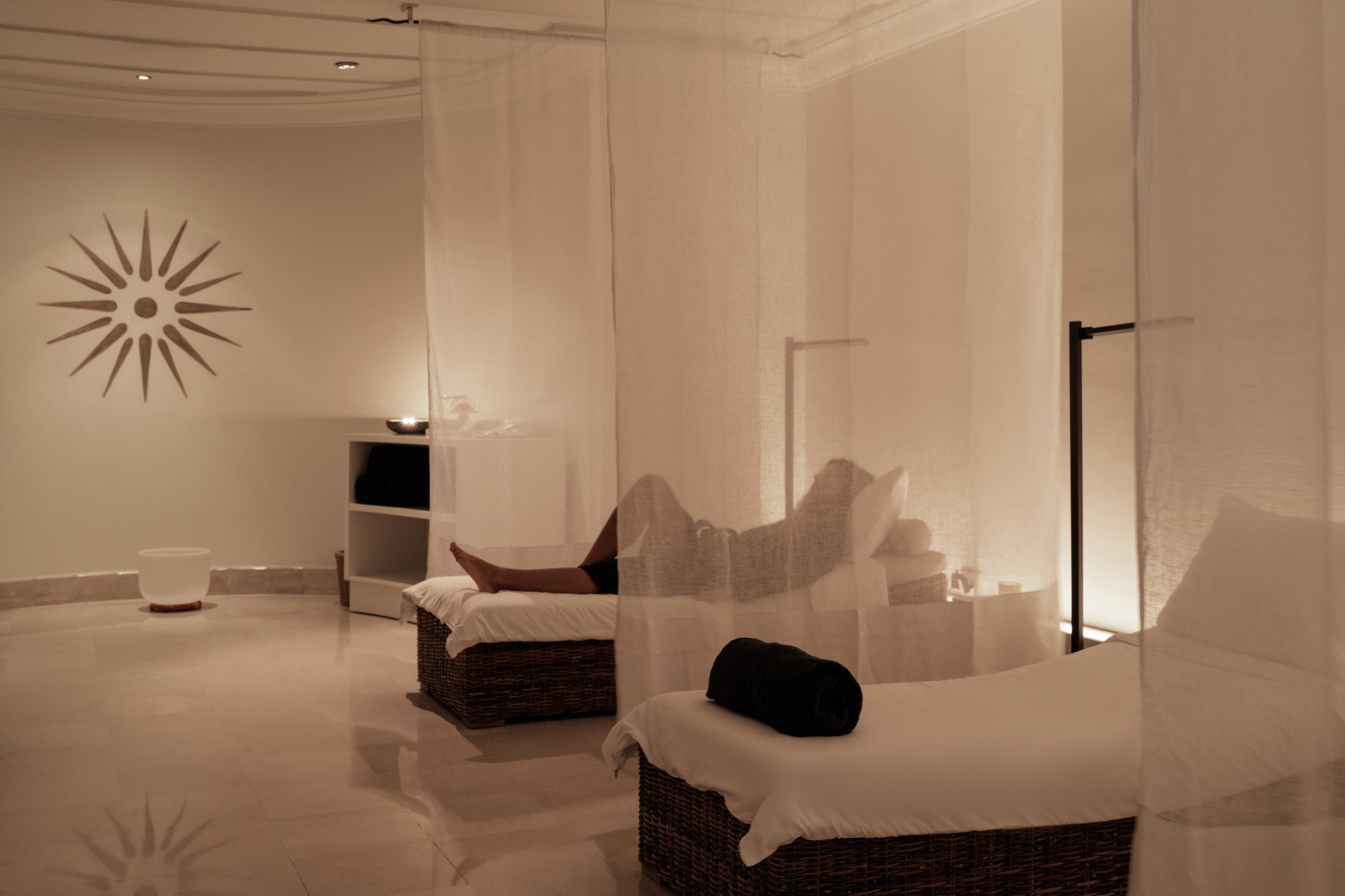 Thalasso Spa at Anassa in Cyprus featuring a guest lying on one of the relaxation beds behind a sheer curtain in a soothing pale room