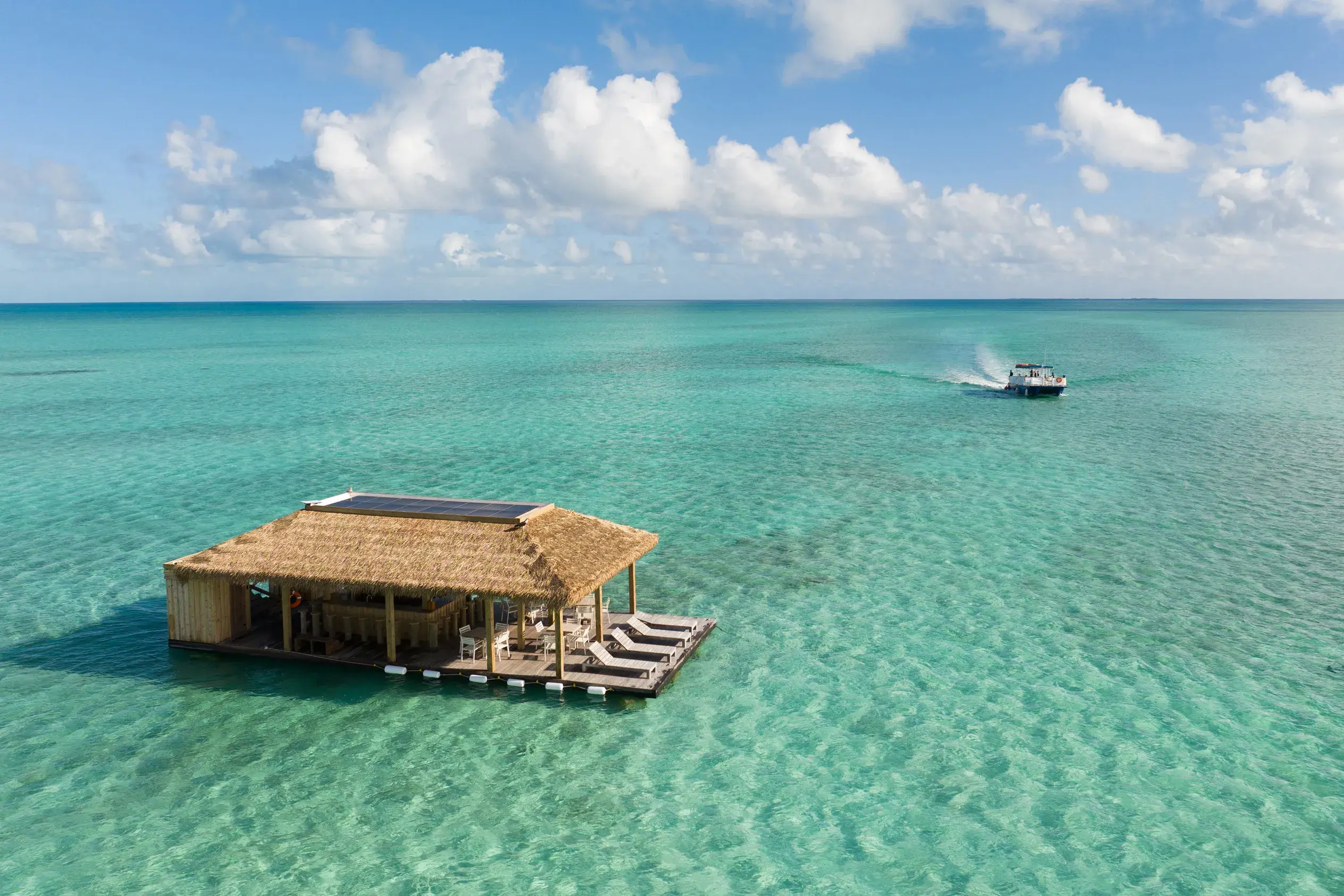 Hangover Tiki Bar at Ambergris Cay in Turks & Caicos surrounded by water with a boat in the background