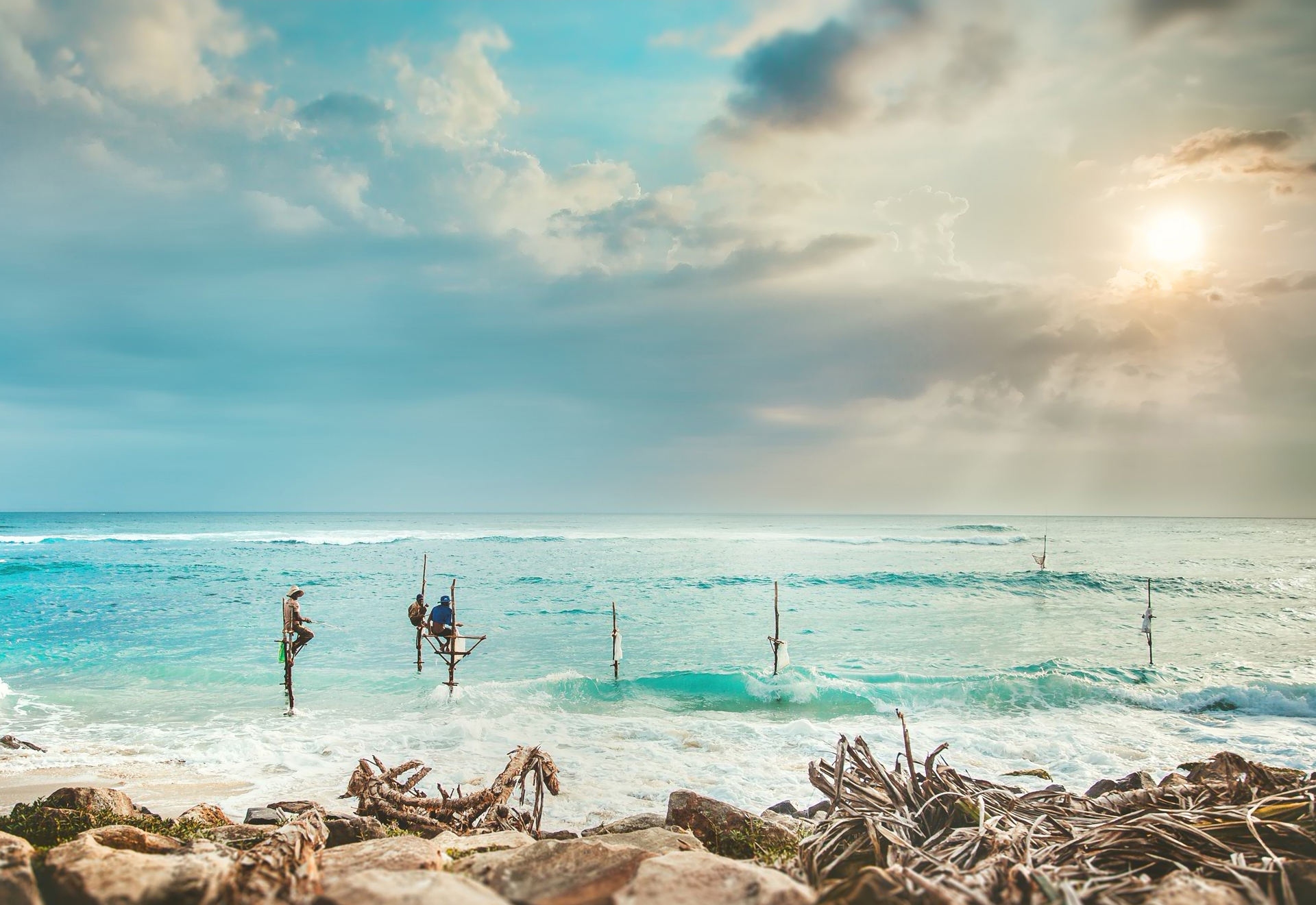 Three people fishing from stilts in the sea