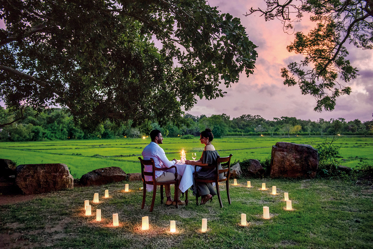 Couple private dining at sunset surrounded by a circle of candles