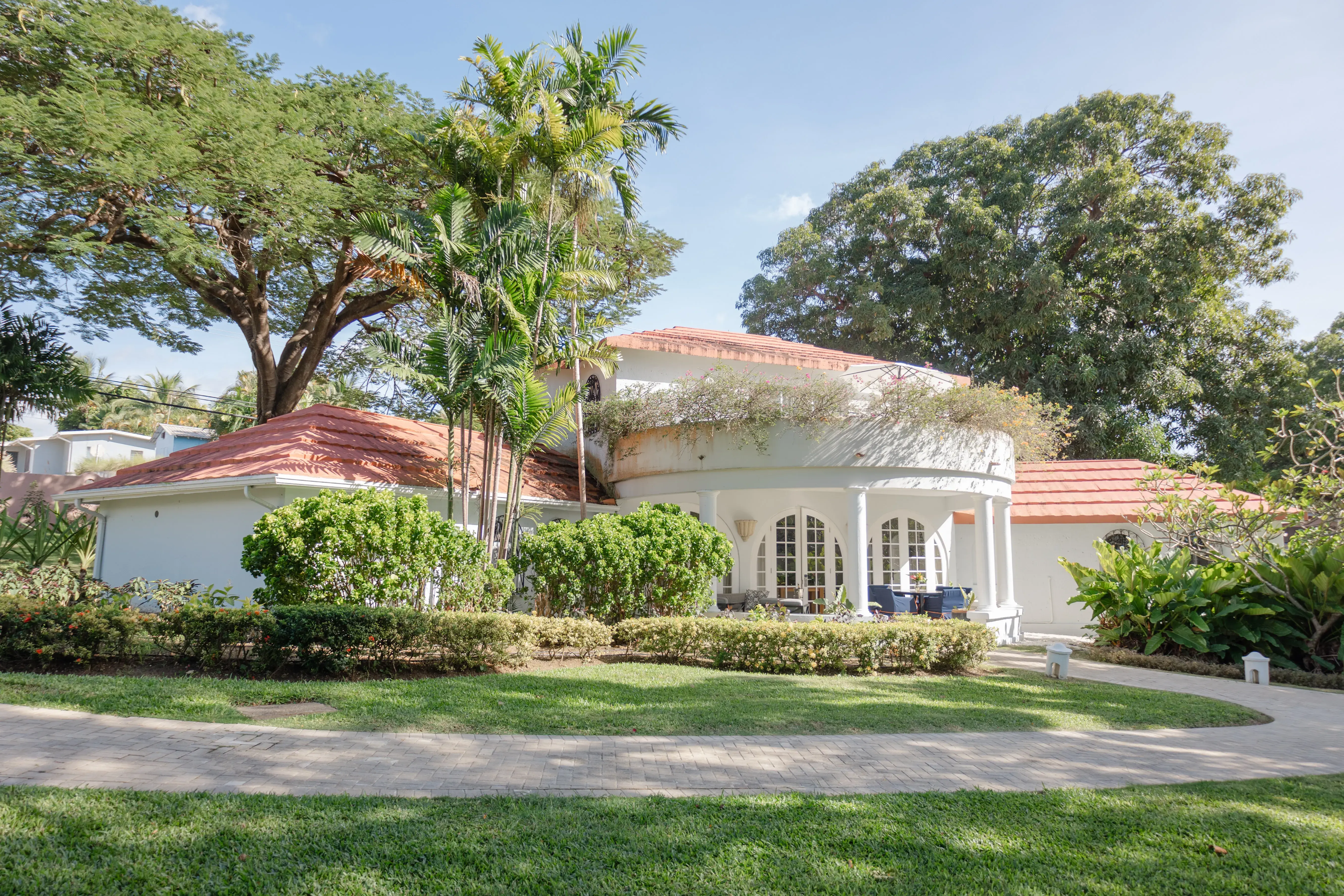 Elegant three-bedroom villa at Fairmont Royal Pavilion Barbados surrounded by tropical gardens, featuring a red tiled roof and spacious outdoor living area