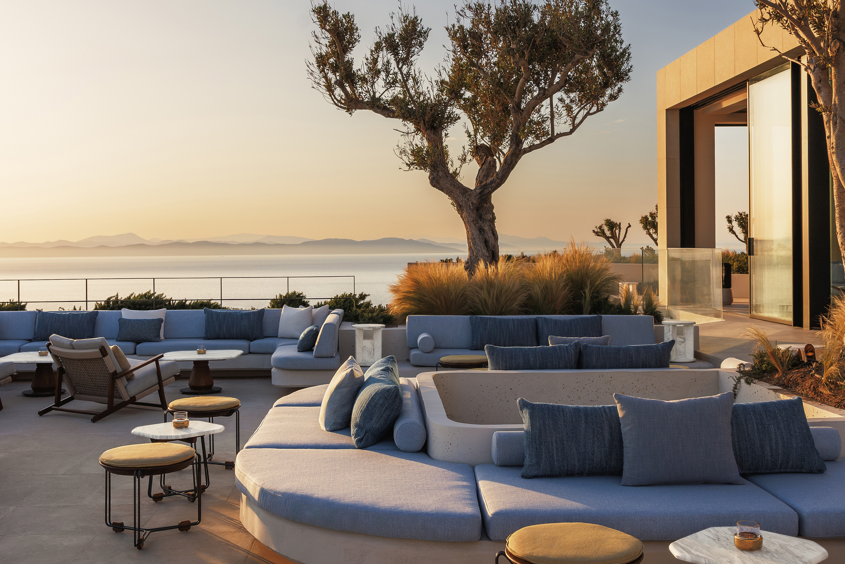 Blue cushioned sofas on the terrace of Kosmos restaurant at sunset