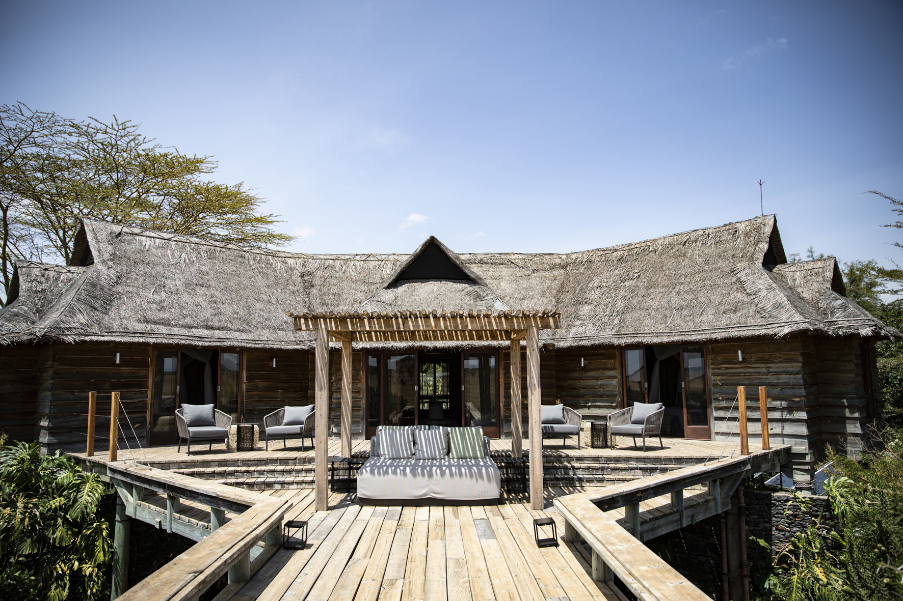 The exterior of a large thatched villa with a cabana and wooden walkway