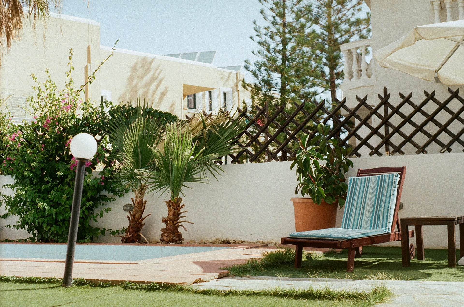 A sun lounger, white buildings and green plants