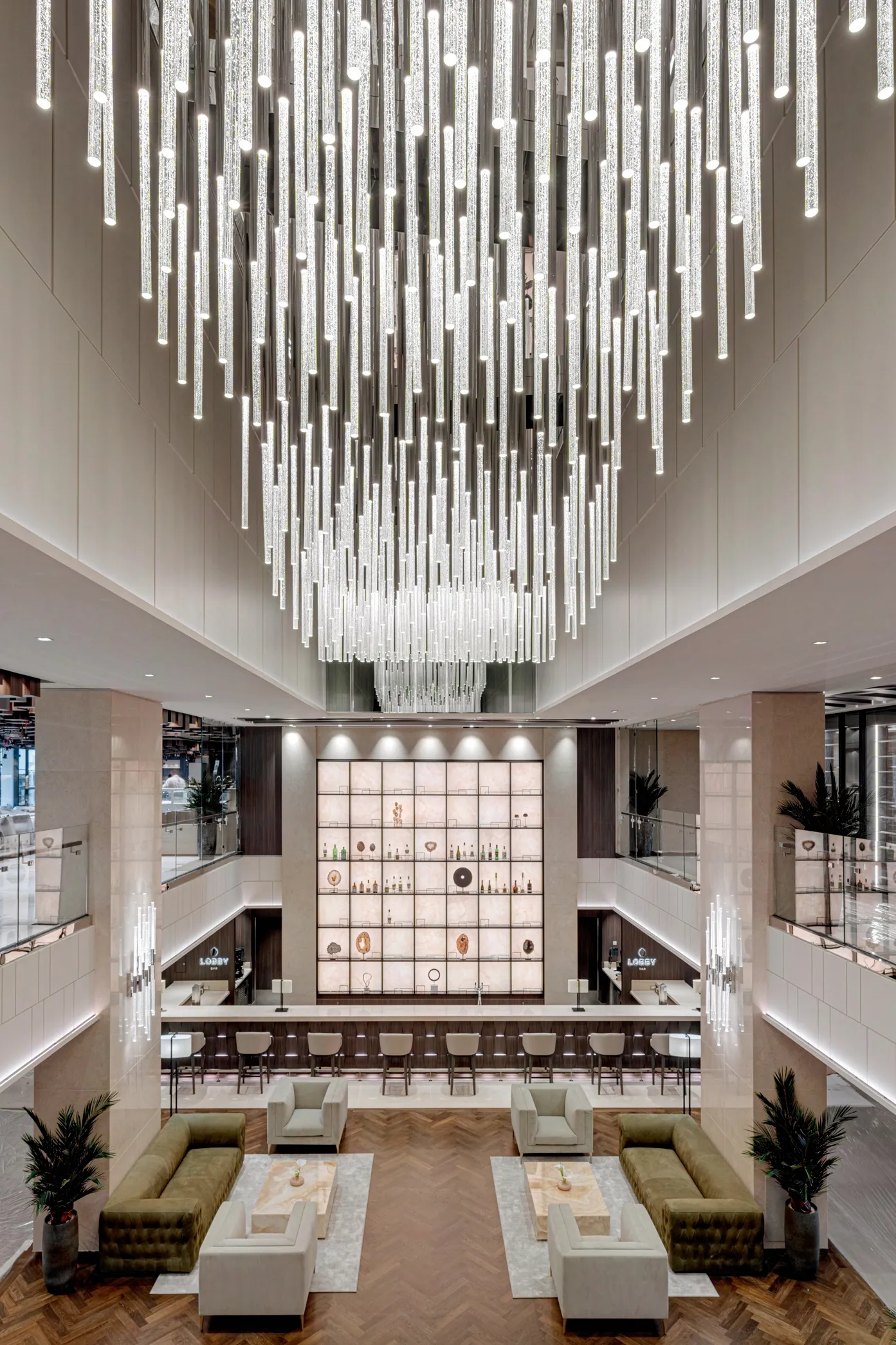 Contemporary cruise ship lobby featuring a striking chandelier, elegant seating, and a sleek bar area.