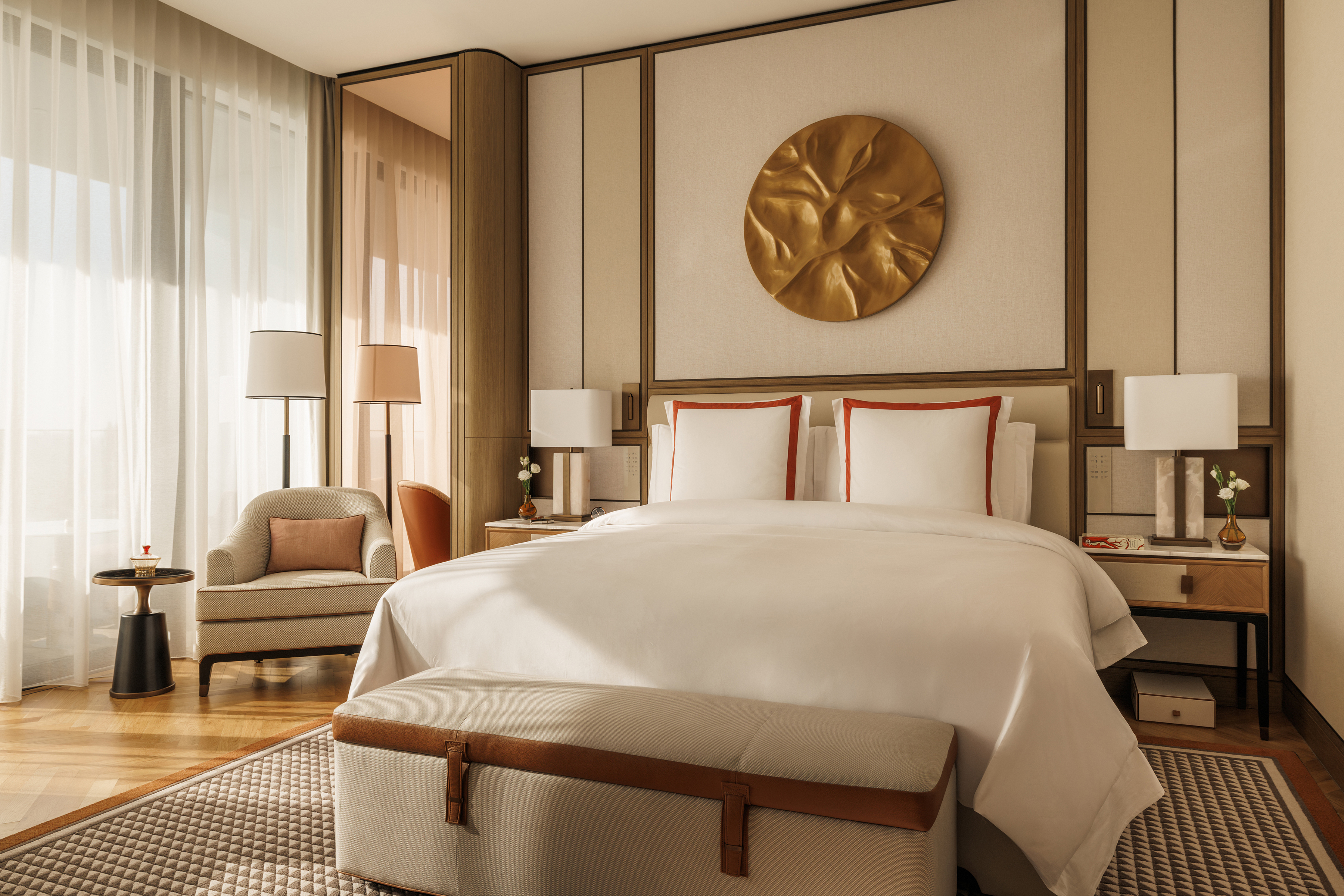 An elegant room at Jumeirah Marsa Al Arab decorated in cream and red furniture with a large gold art piece on the wall