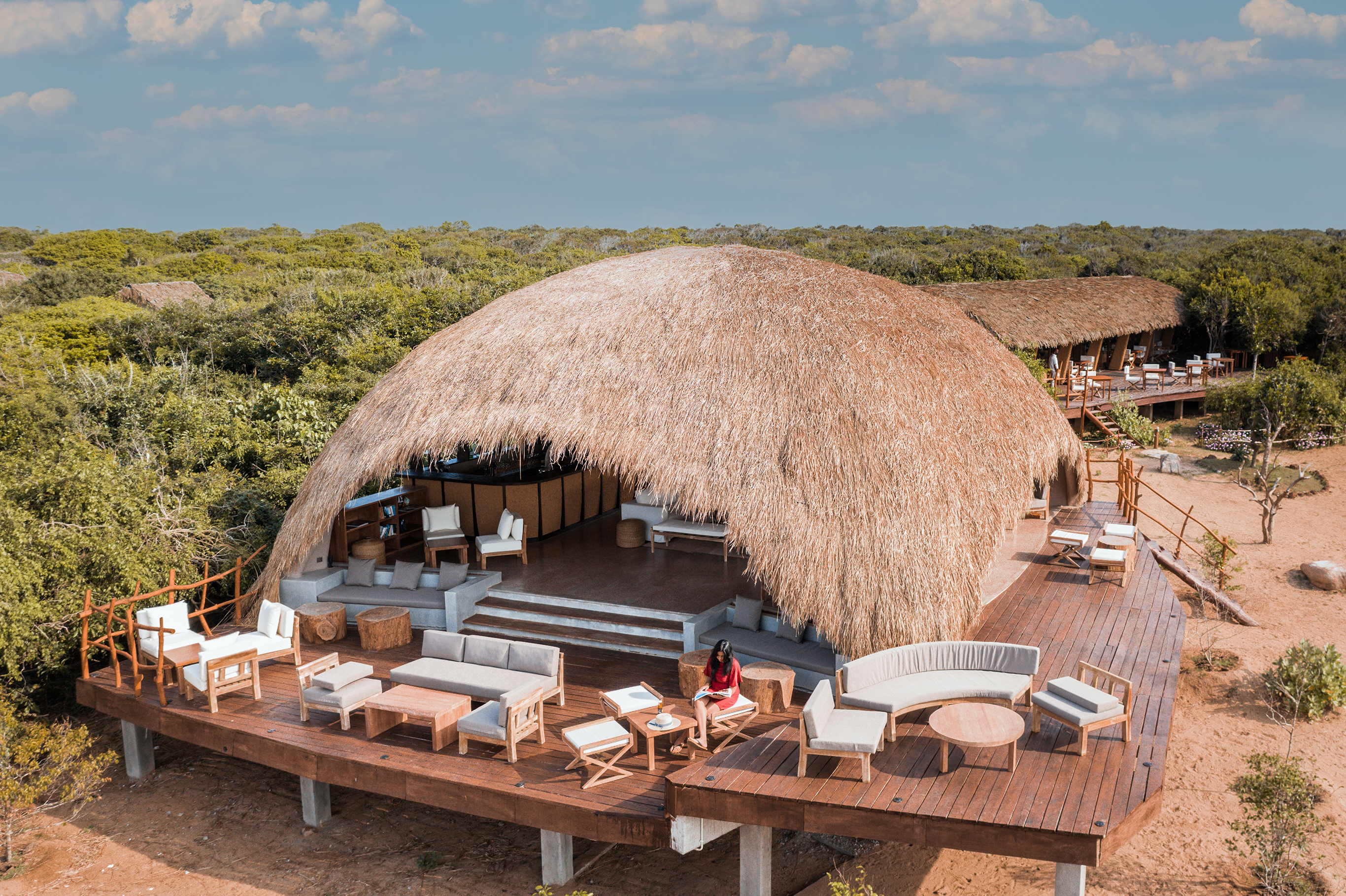 Thatched domed bar of Uga Chena Huts with wooden decking featuring plush sofas