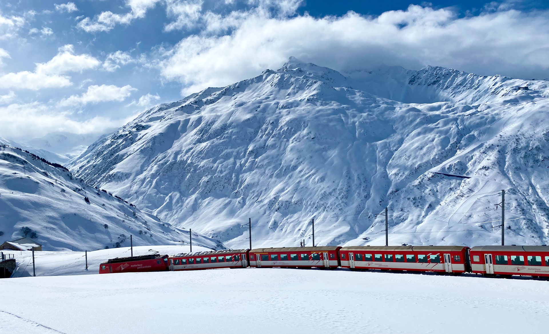 A red train traveling through a snow covered mountain