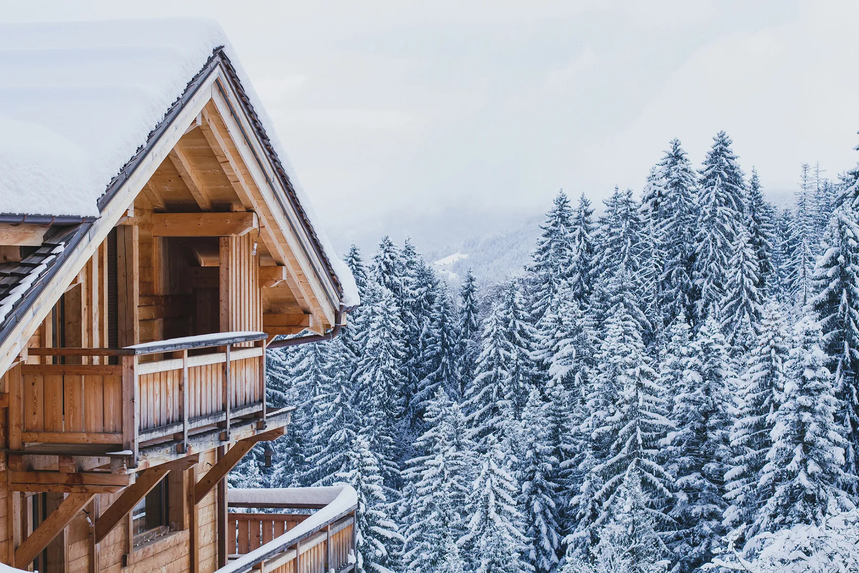 A close up image of a ski chalet balcony amid a snowy fir tree forest 