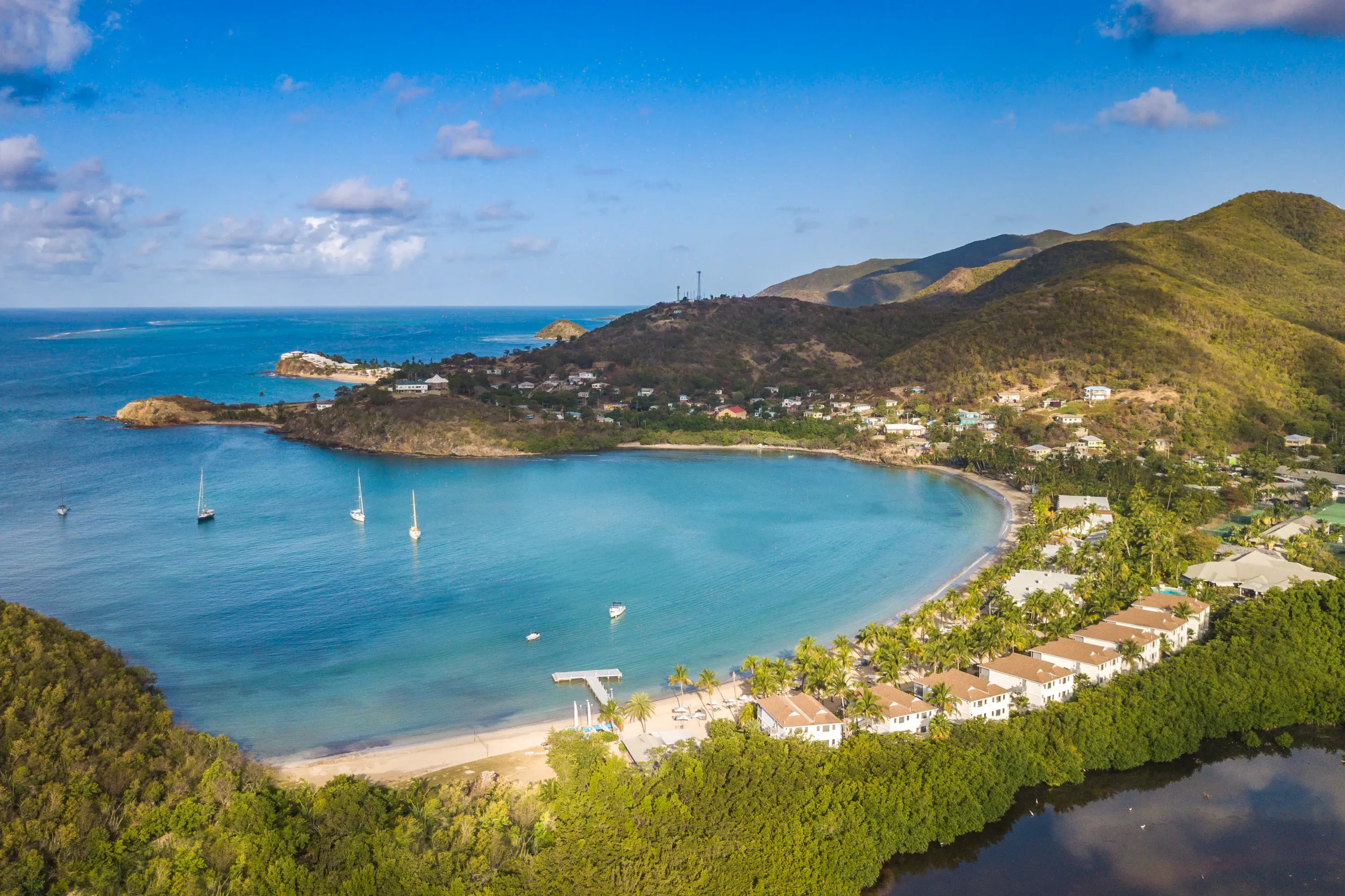 An elevated shot of Carlisle Bay featuirng the hotel buildings dotted between lush greenery and yachts anchored in the sea
