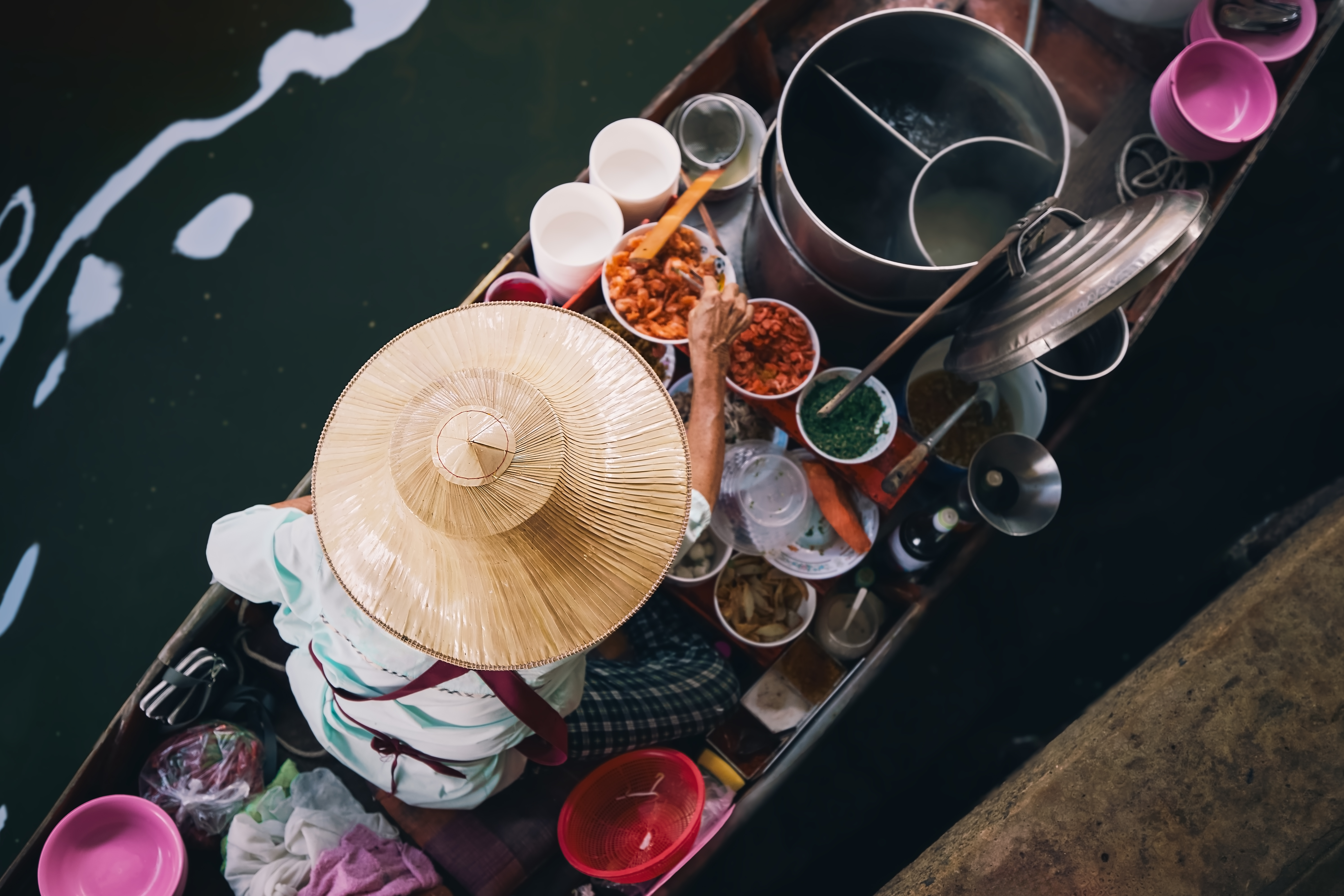 A person preparing food on a small wooden baot