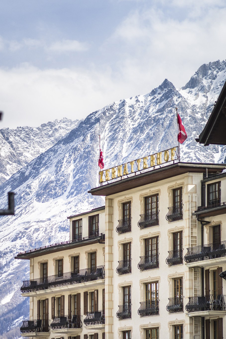 A close up of the exterior of Grand Hotel Zermatterhof with the mountains in the background