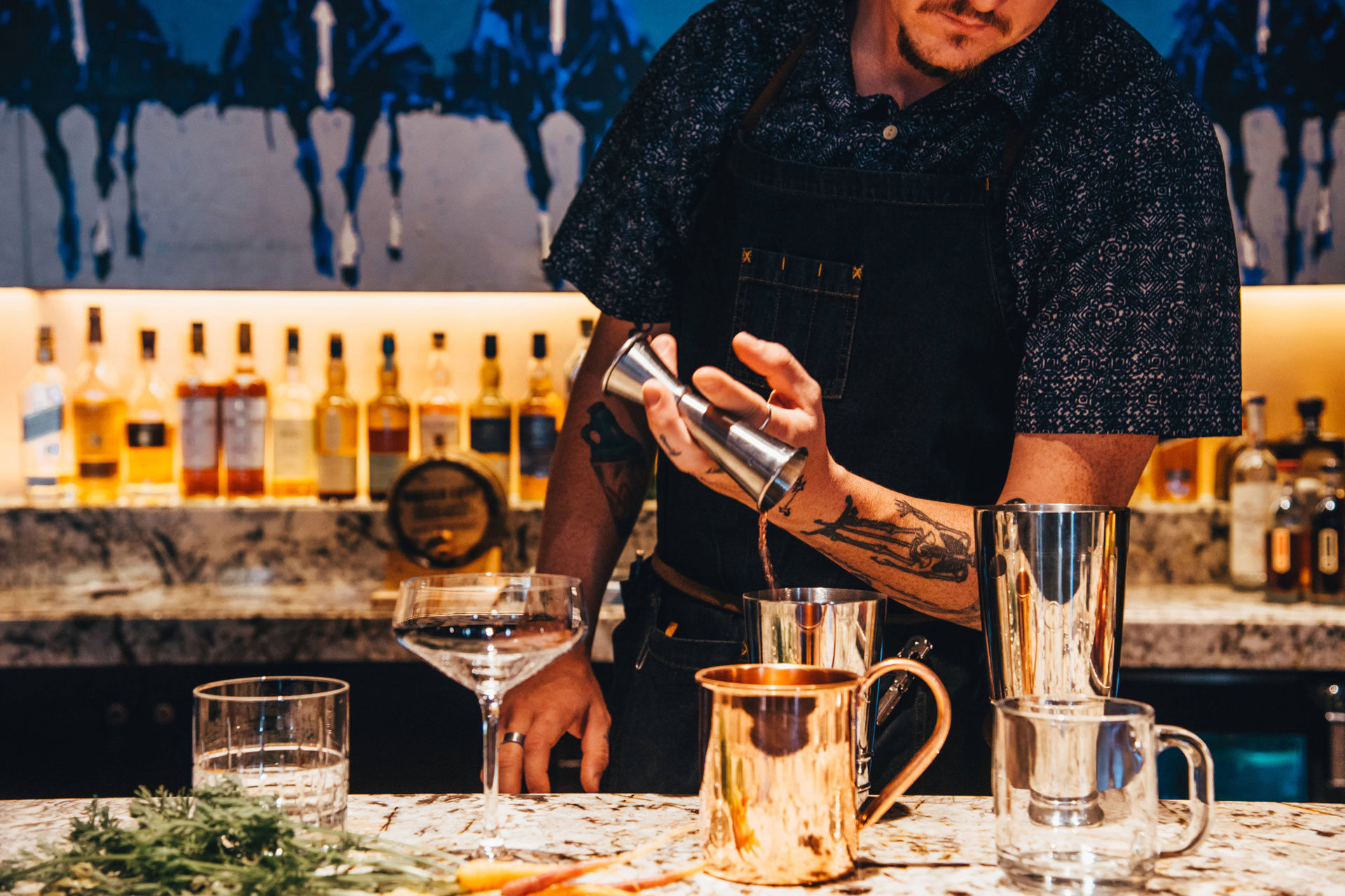A bartender behind a bar pouring a drink