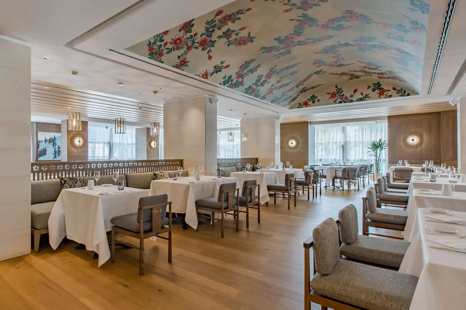 The Savoy restaurant at Grand Hotel Savoia with tables set for a meal beneath a painted mural ceiling 