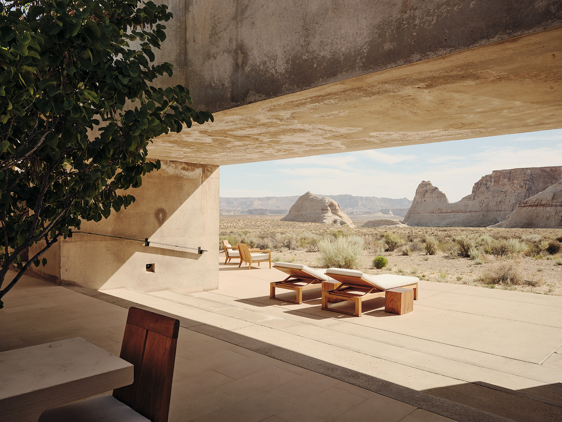 A concrete sun deck lined with sun loungers overlooks a rocky Utah landscape
