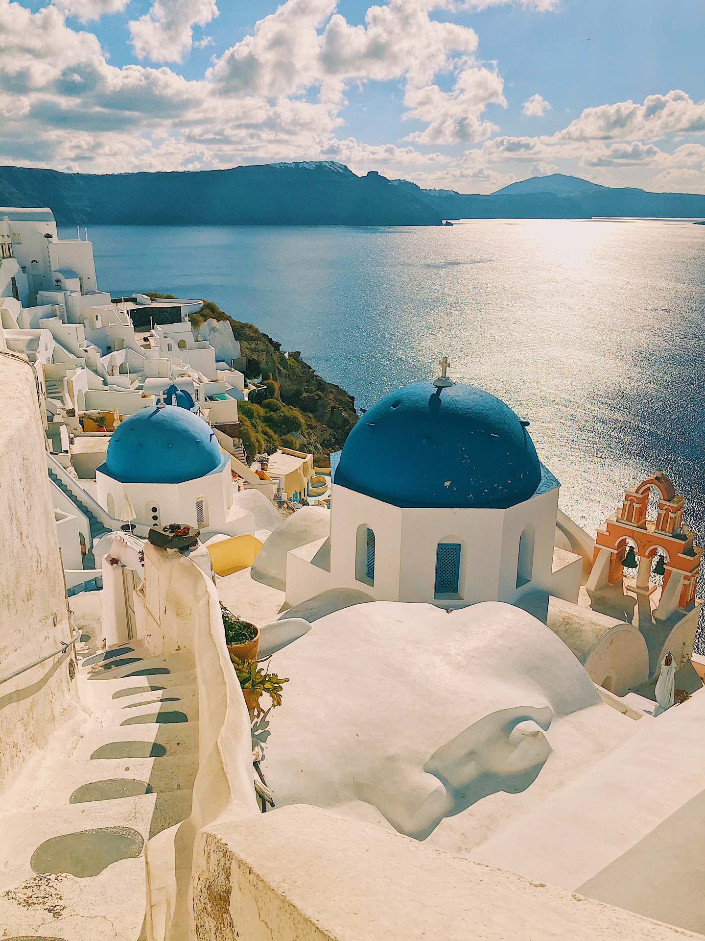 Coastal Greek town with white buildings and blue roofs next to the sea