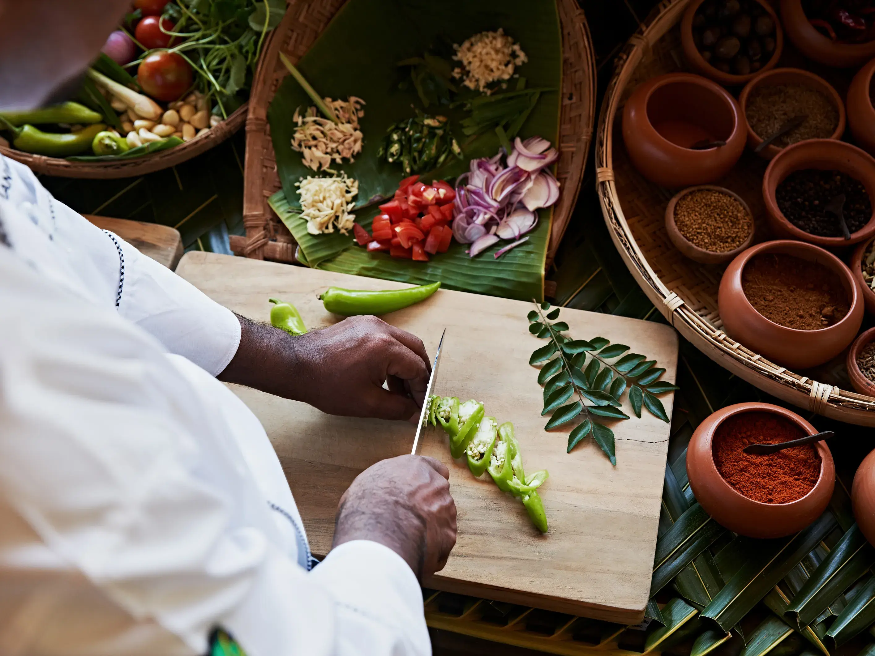 Chef preparing fresh vegetables and spices for a traditional Sri Lankan cooking class at Amanwella luxury resort.