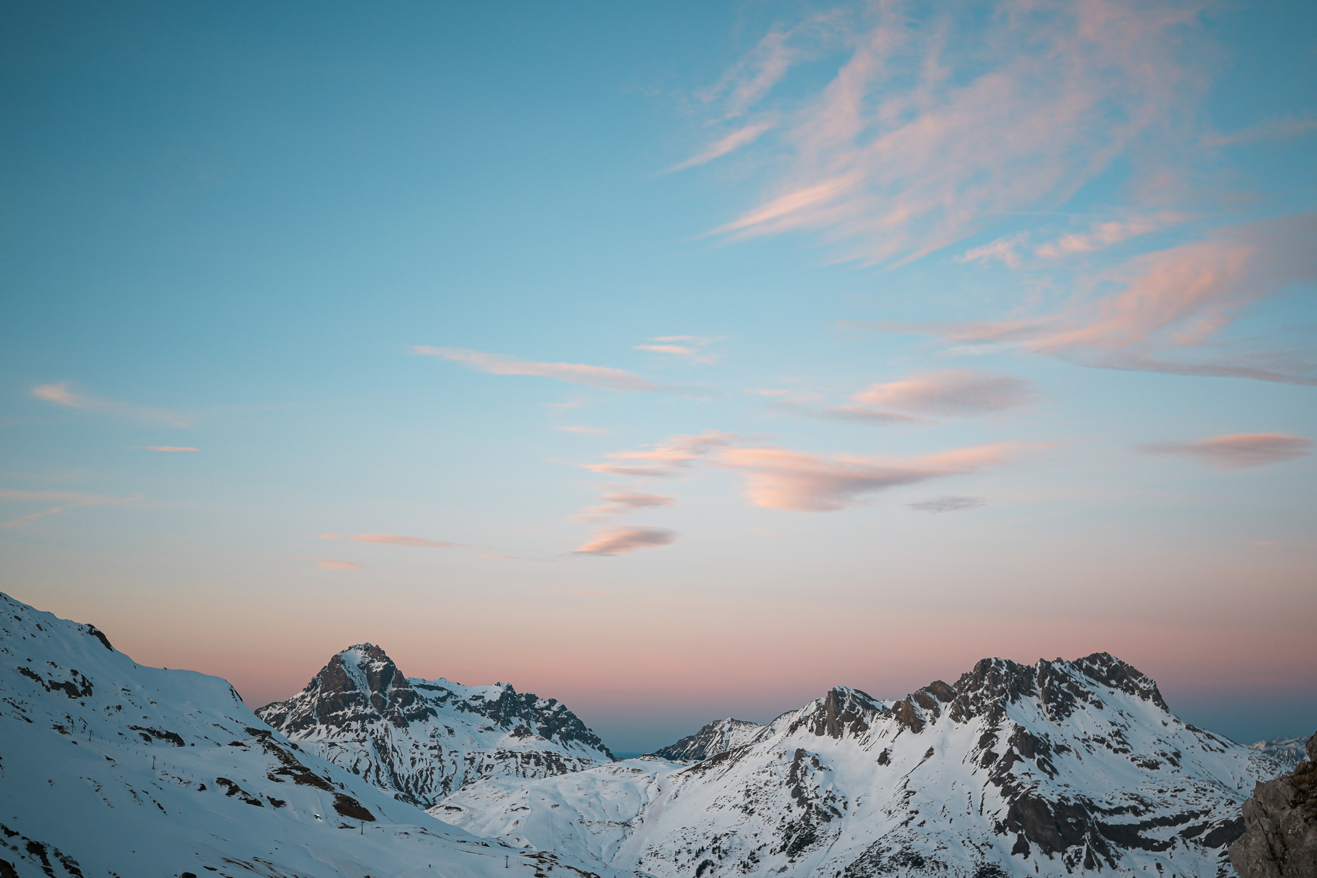 A view of the top of snowy mountains as the sun rises