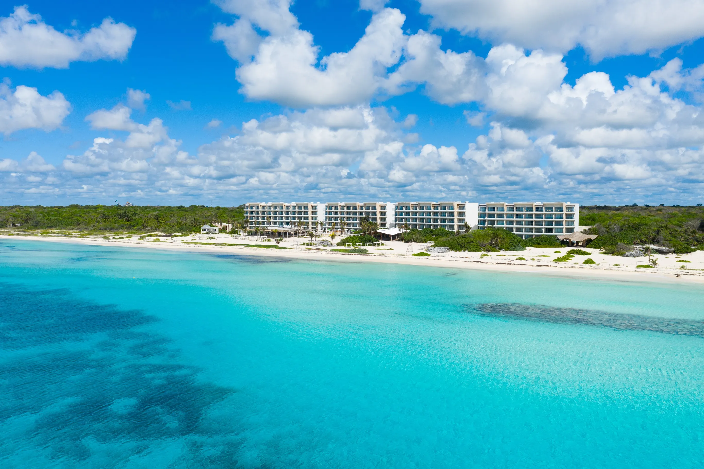 Aerial view of beachfront resort set against turquoise sea and white sand beach.