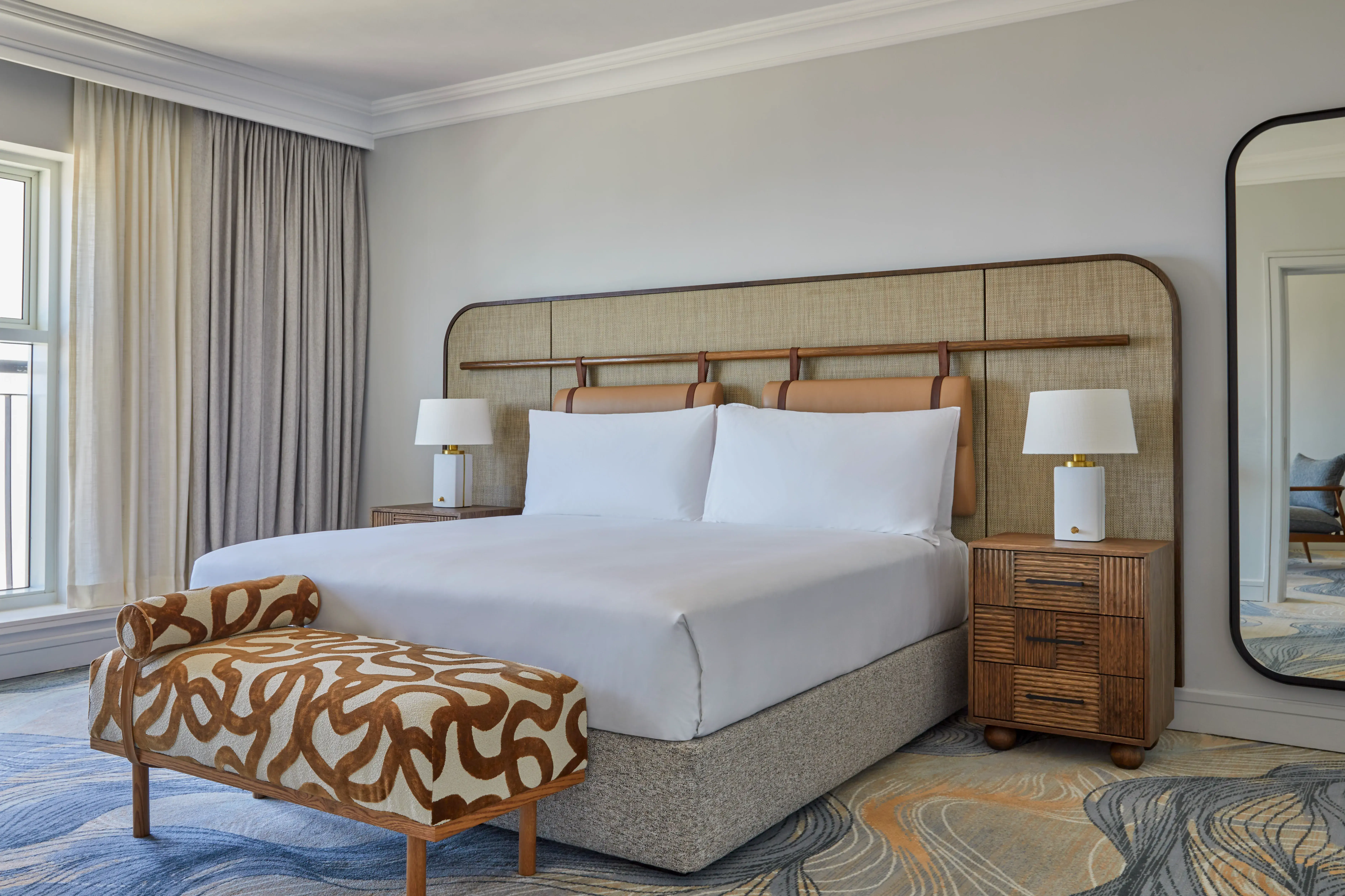 A One Bedroom Suite at InterContinental Table Bay featuring a comfy bed and contemporary furnishings including a patterned ottoman