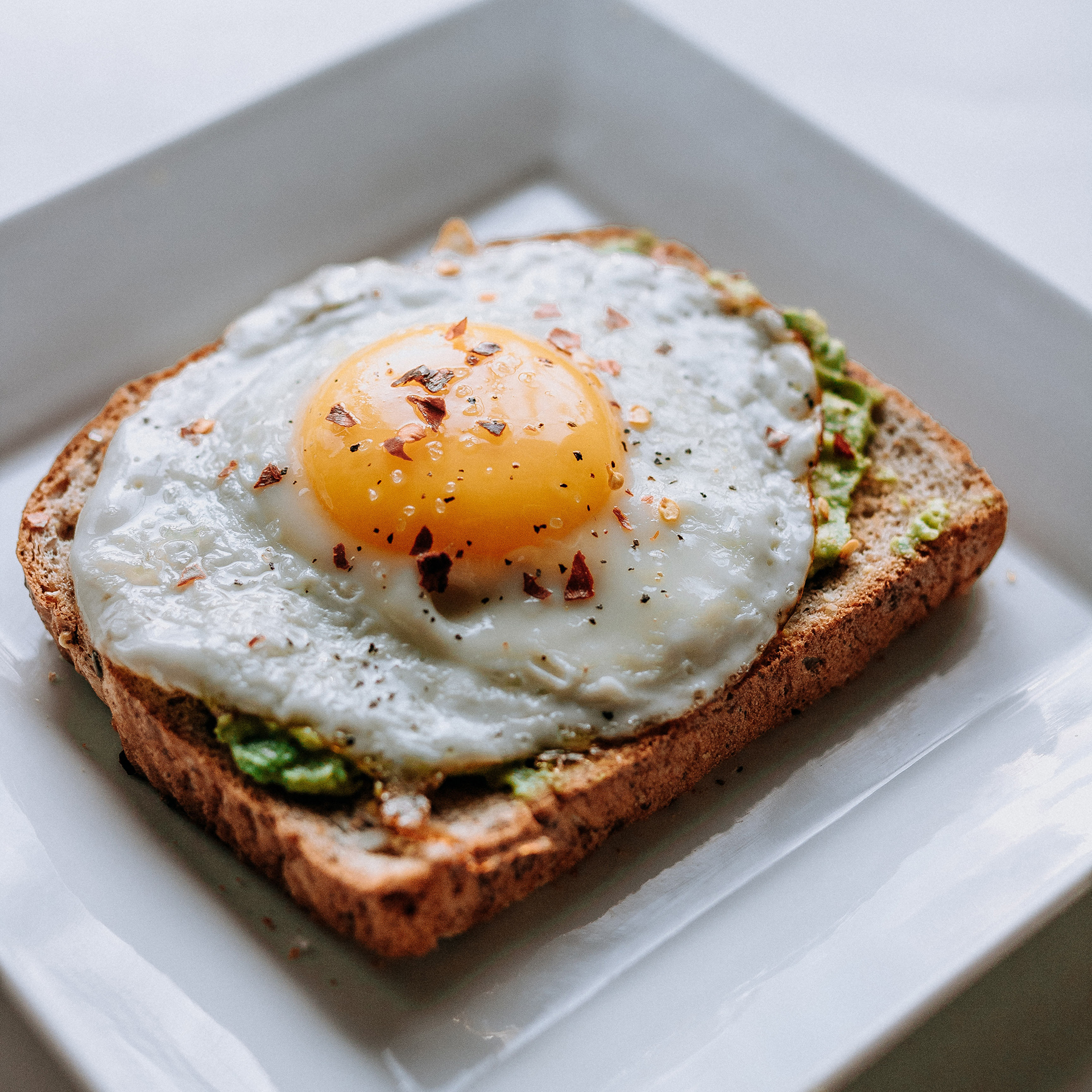 Bread with sunny side-up egg served on white ceramic plate