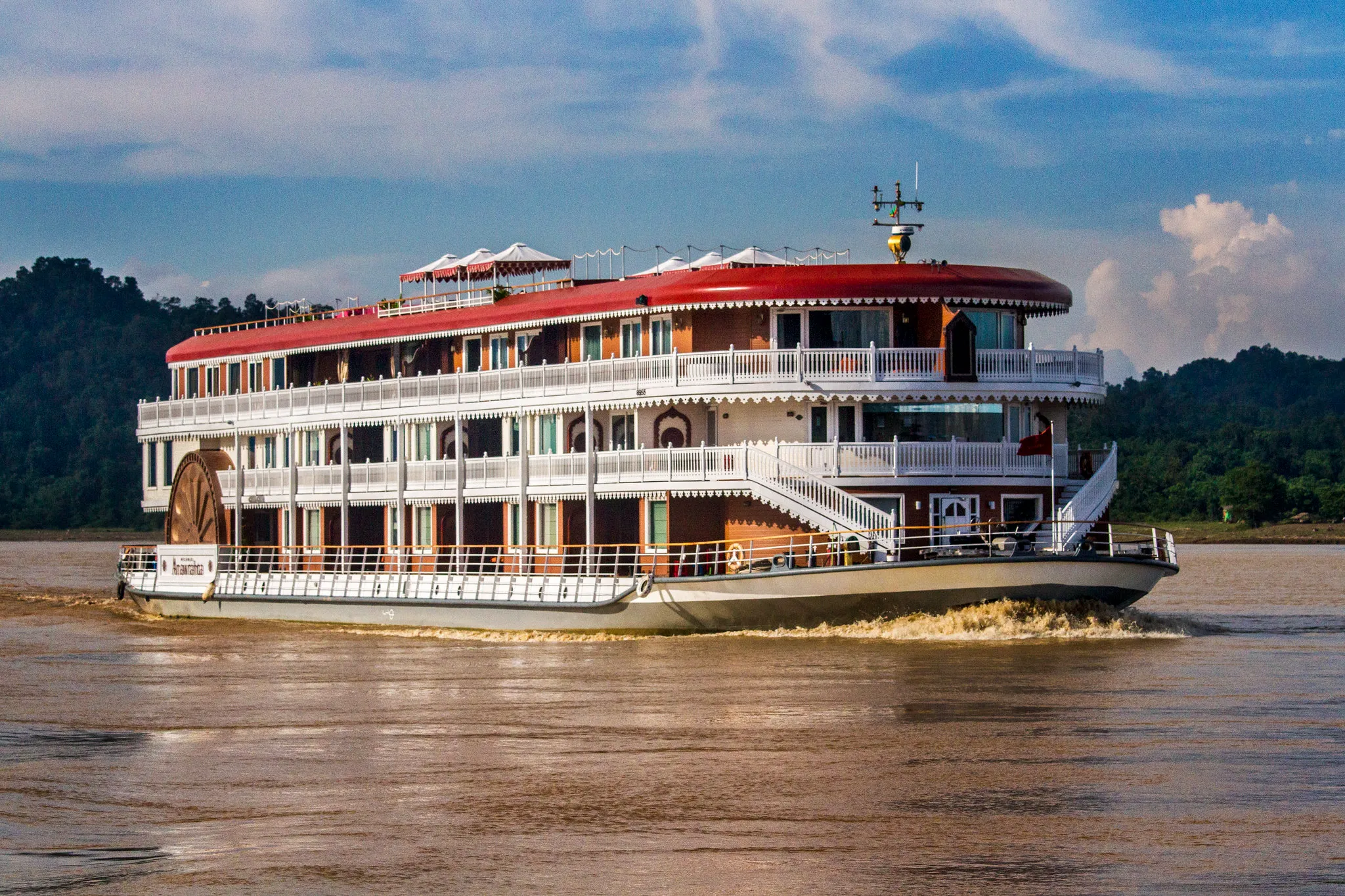 Heritage Line river cruise ship with traditional design sailing past green hills on a calm waterway.