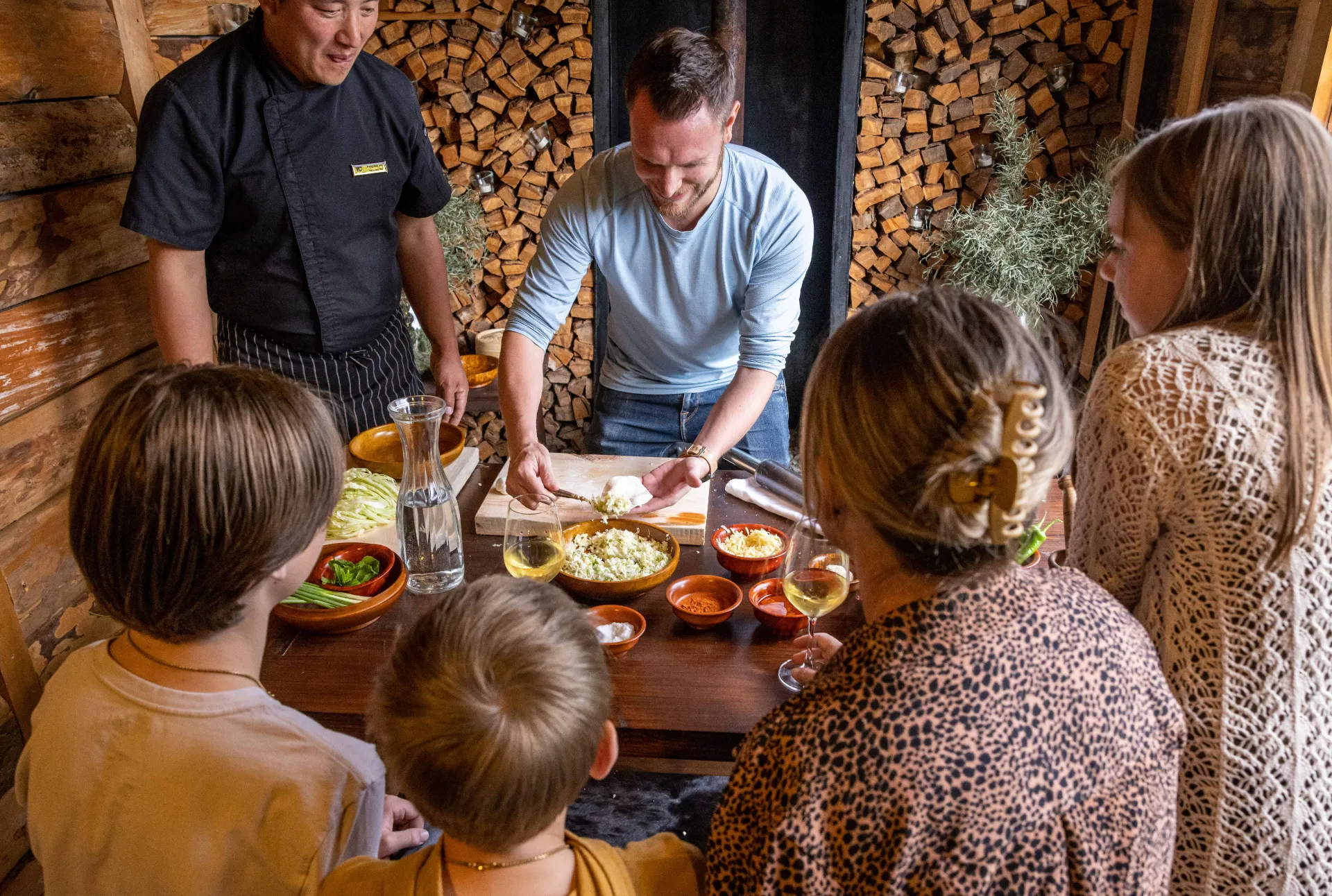 Hands‑on cooking class with guests preparing food at a wooden table with a chef.
