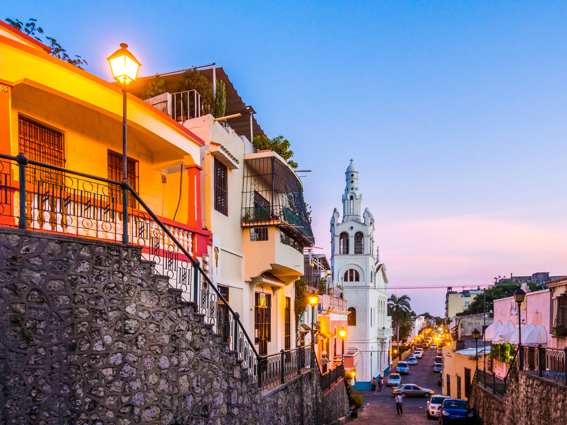 A central district of Santo Domingo with colourful buildings and cars lining the street