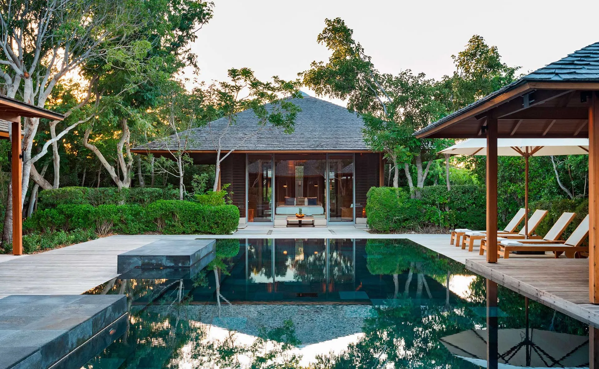 Private pavilion at Amanyara with a tranquil pool surrounded by lush greenery and wooden decking.