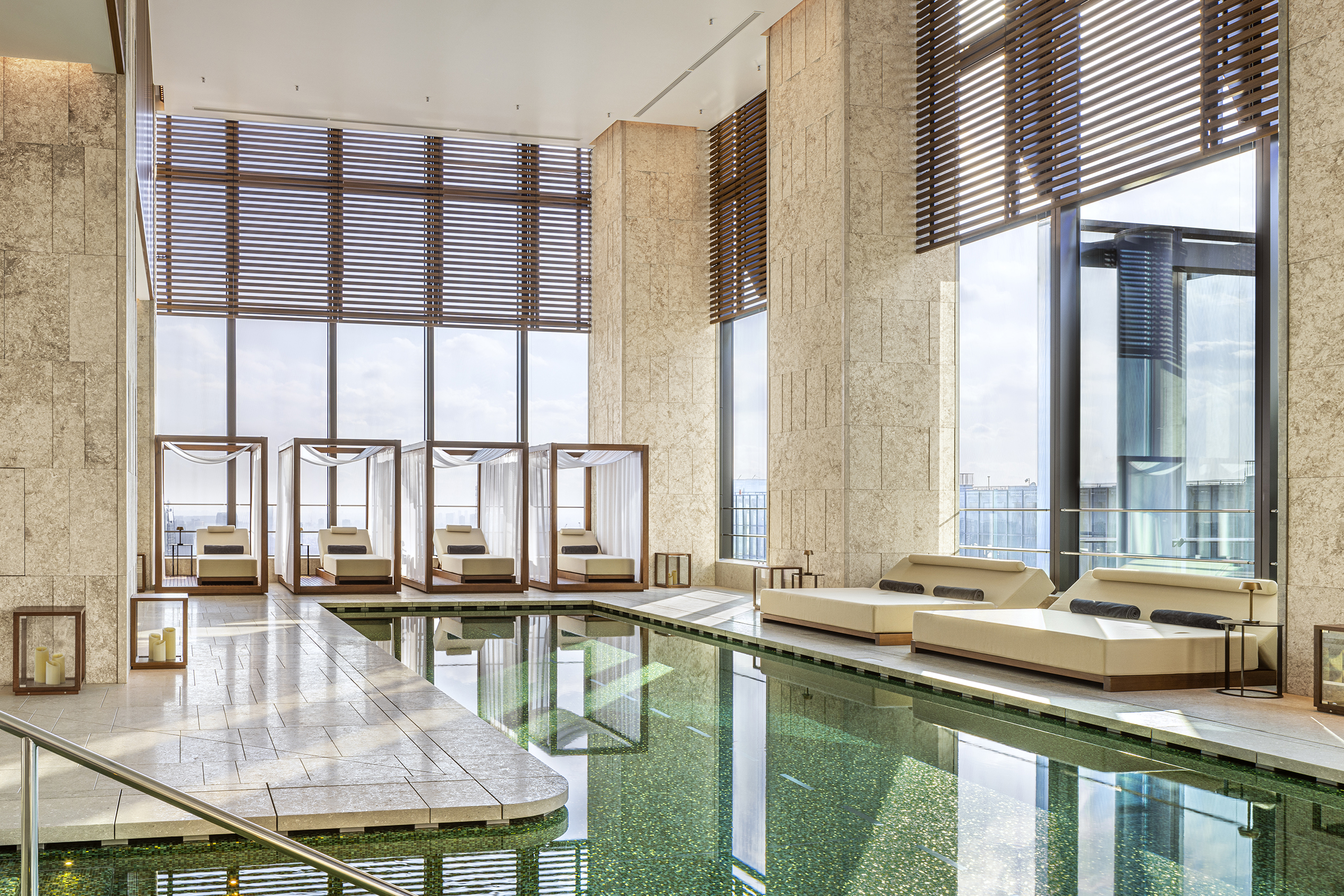 A light and airy pool area with six lounge beds set against floor to ceiling windows