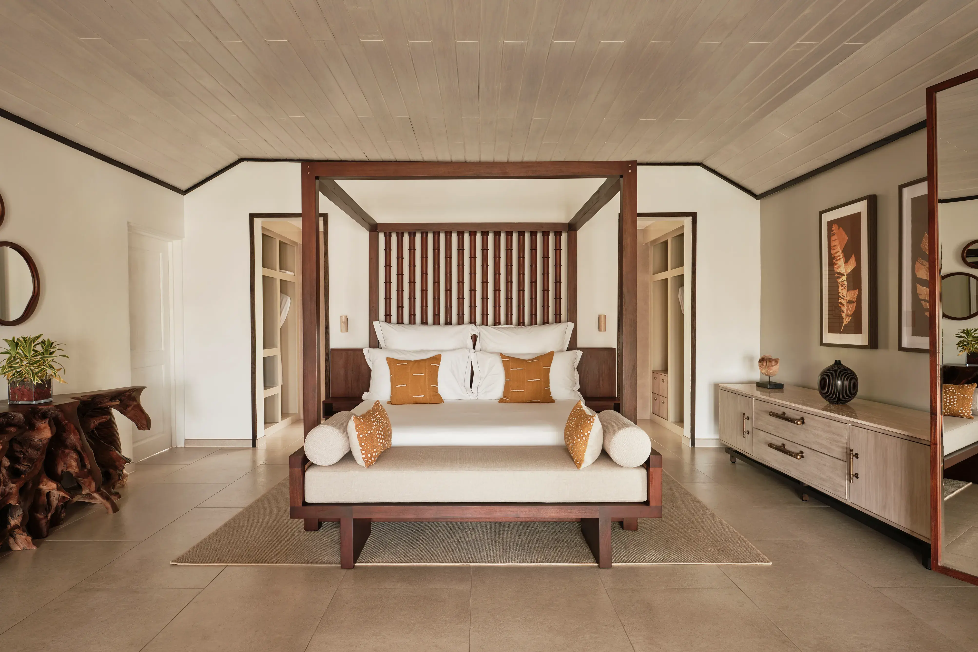 The bedroom of a Garden Suite at Carlisle Bay featuirng a large wooden four poster bed and warm neutral decor and furnishings