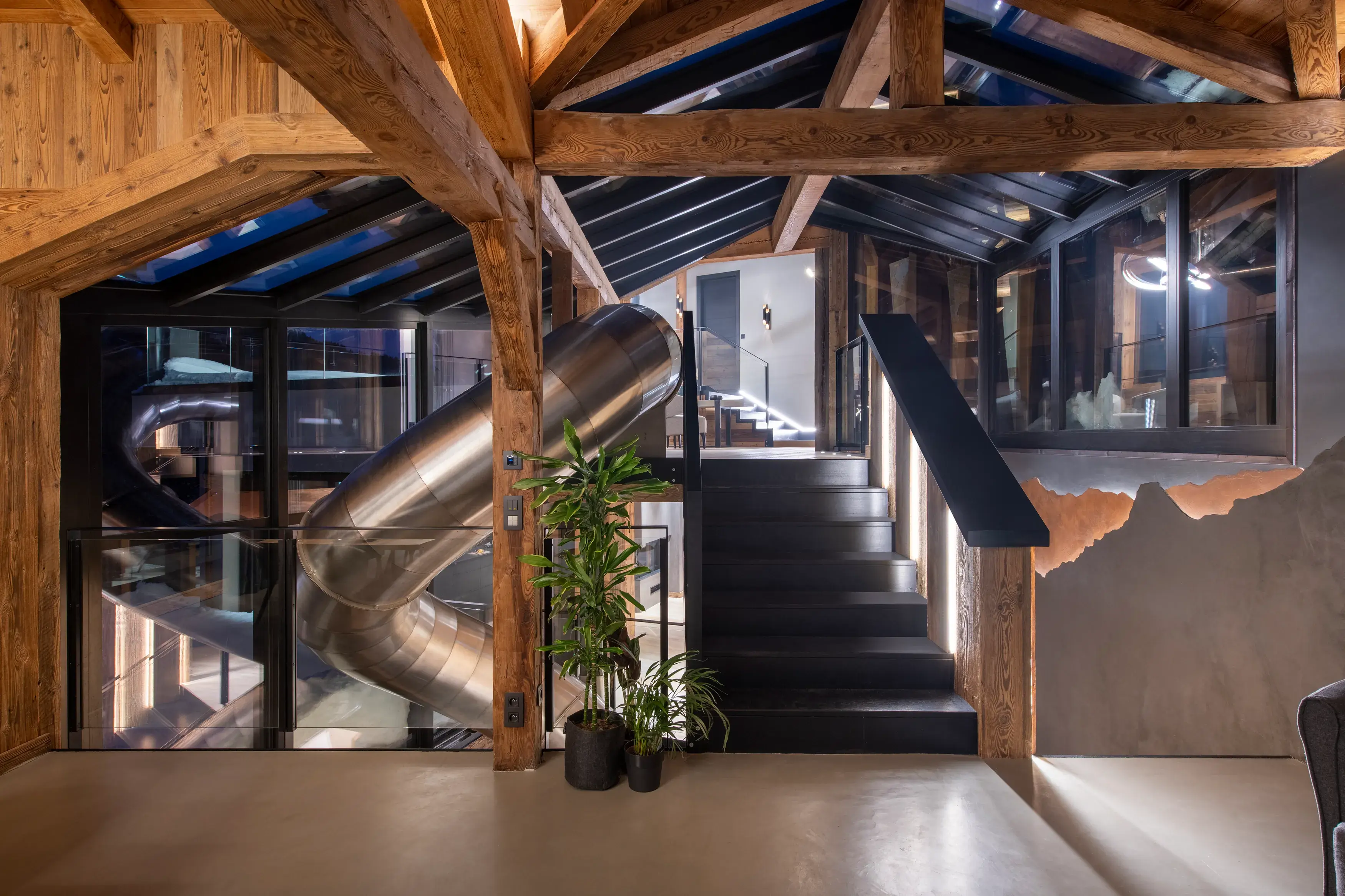 The entrance of Chalet Tataali featuring traditional wooden beams, a small set of stairs leading to a landing and a metal curved slide