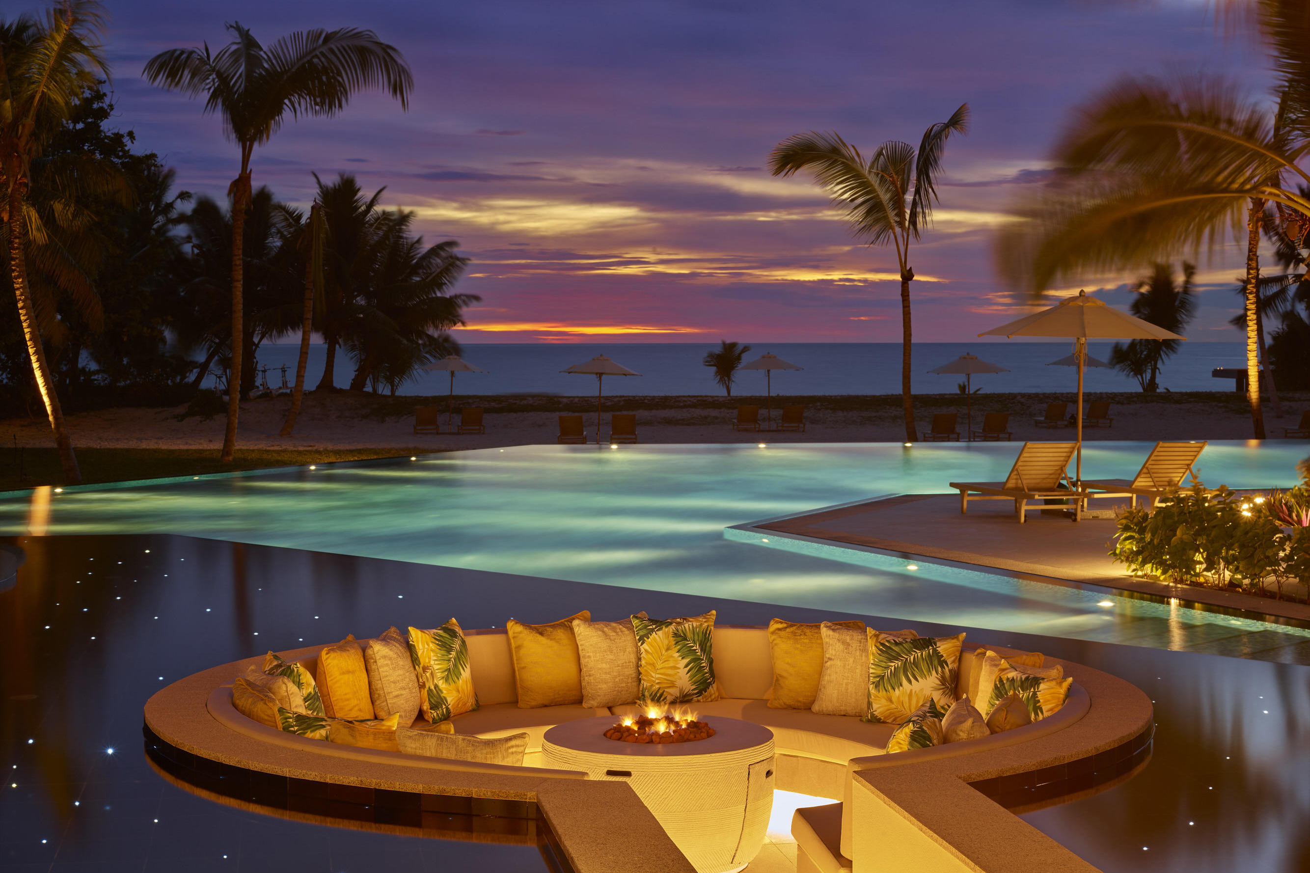 Lavish pool with atmospheric evening lighting at dusk featuring a circular sunken seating area