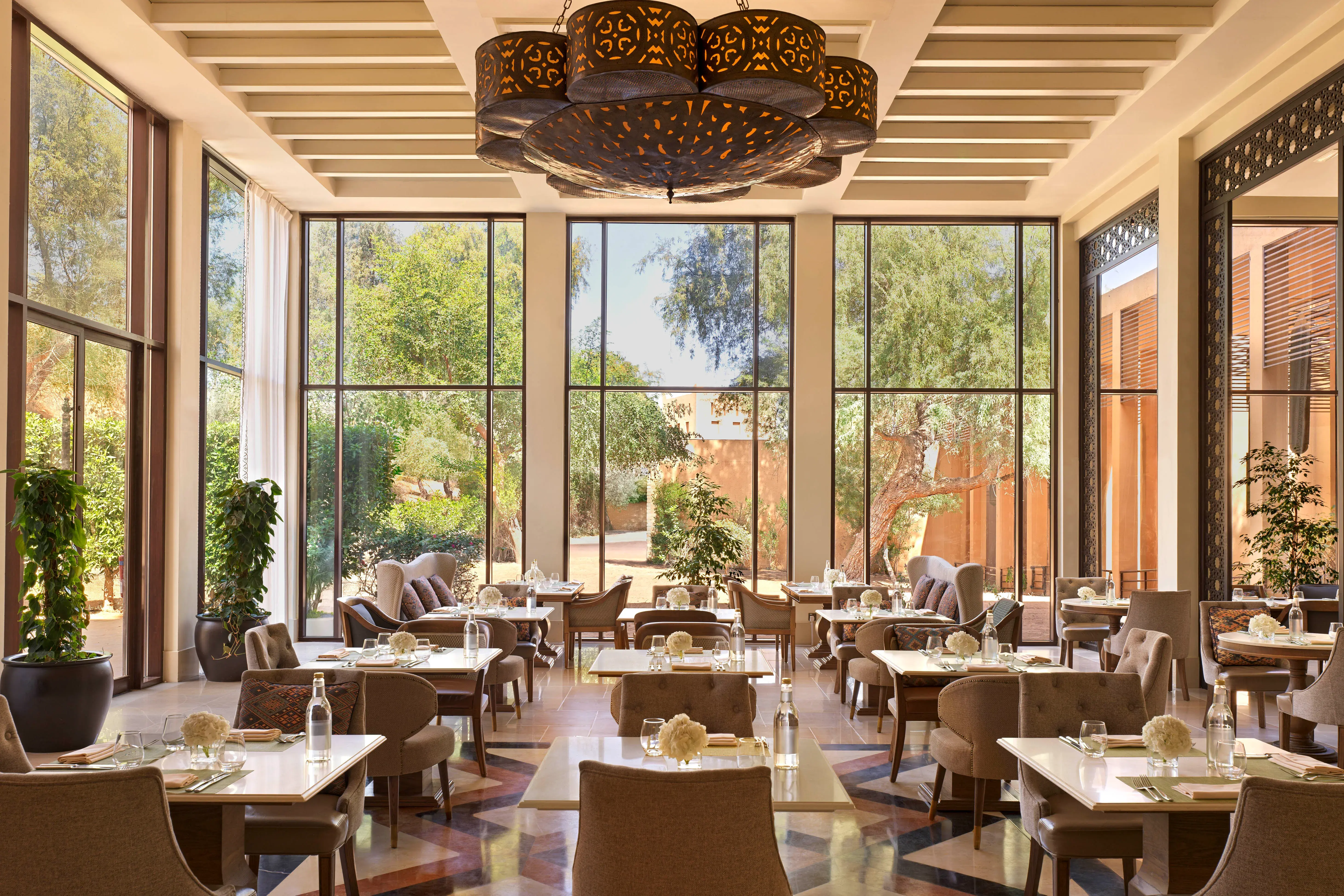 Elegant indoor dining area with floor-to-ceiling windows and modern décor at The Ritz-Carlton Ras Al Khaimah, Al Wadi Desert.