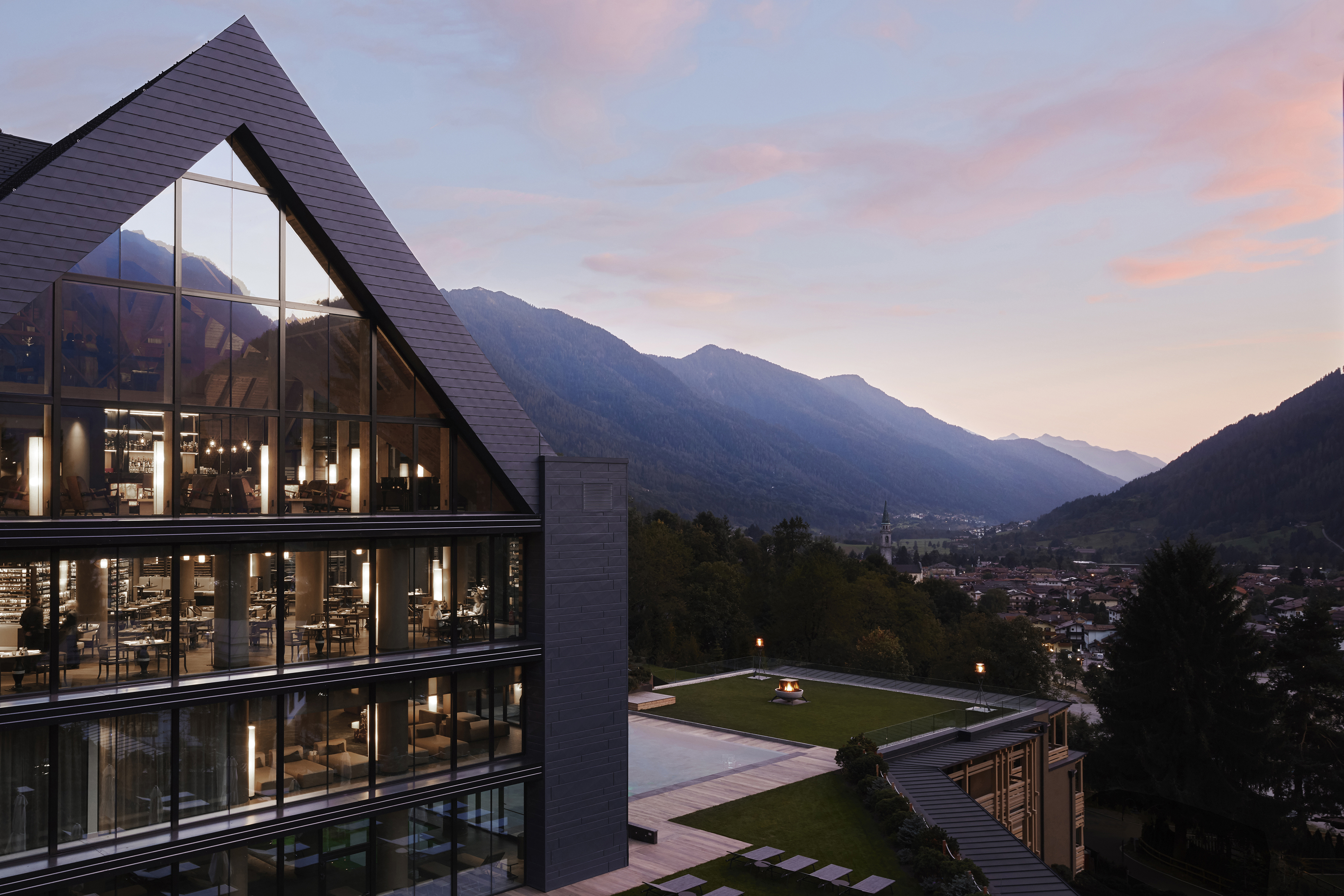 Exterior and outdoor pool of Lefay Dolomiti at sunset with valley laid out behind