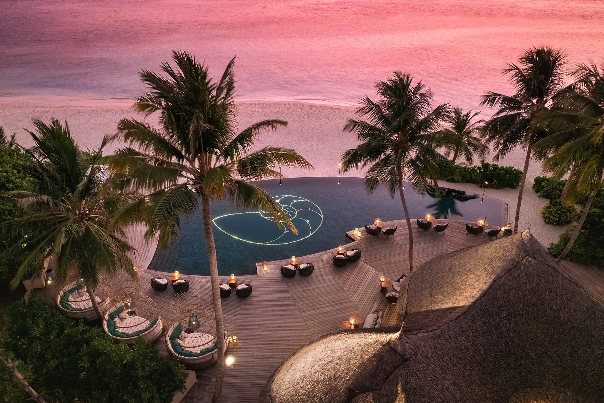 Romantic sunset view of Naiboli Bar at The Nautilus in the Maldives with beachfront pool, palm trees, and ocean backdrop.