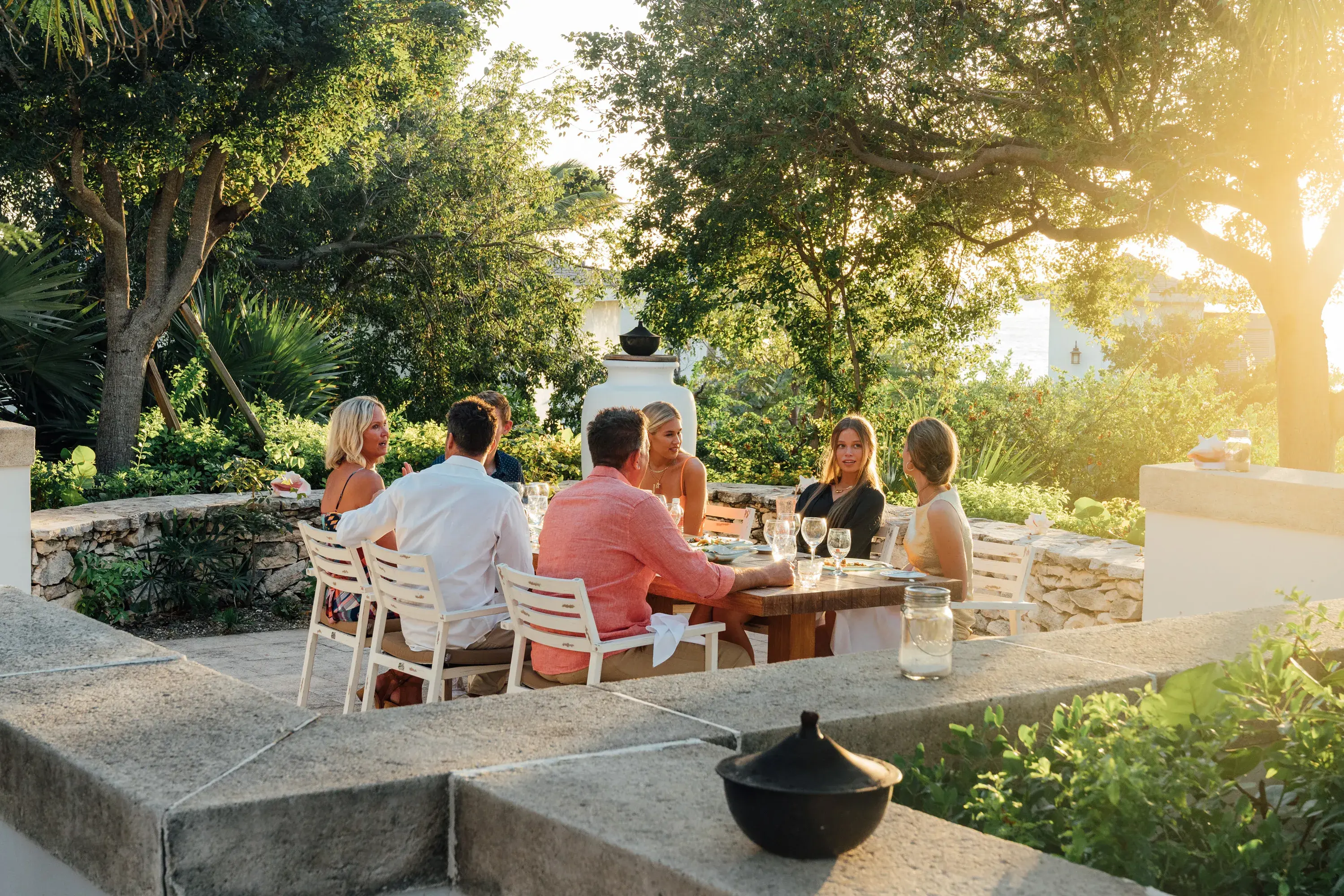 A family enjoying a private dinner at sunset surrounded by greenery