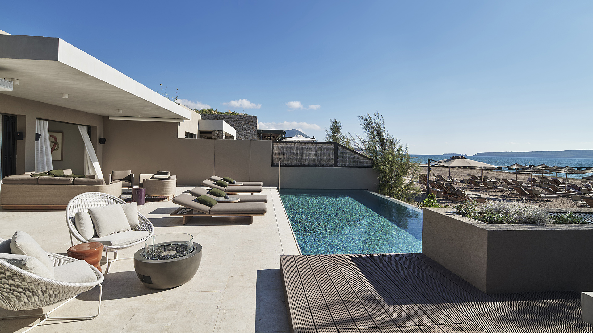 Terrace with loungers, chairs and infinity pool overlooking the beach at W Costa Navarino