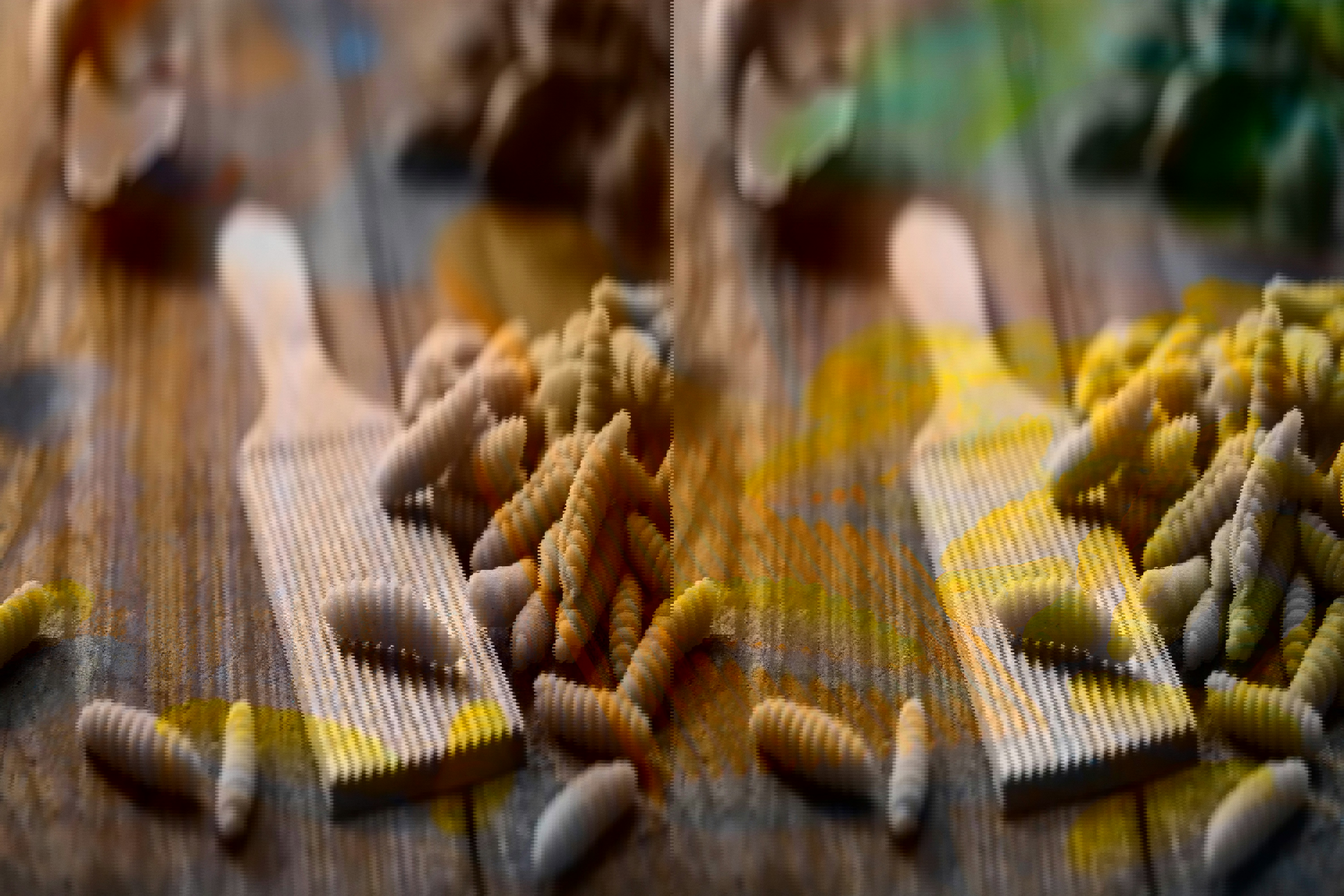 A ribbed pasta board beside a pile of fresh pasta on top of a wooden table
