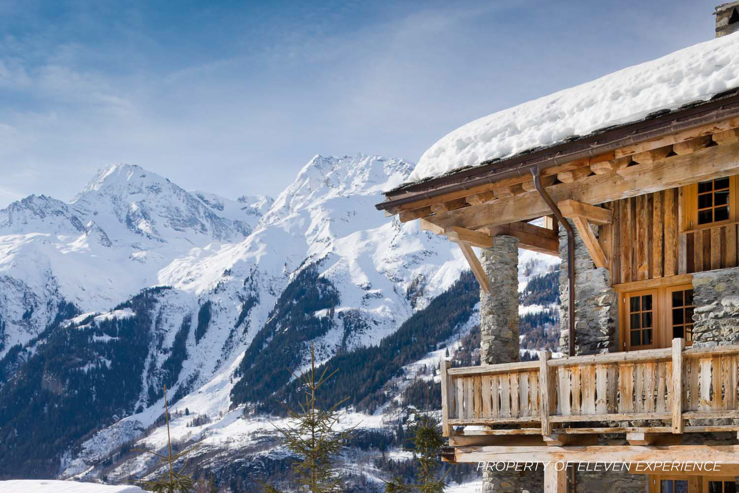 A wooden chalet with snowy mountains in the background