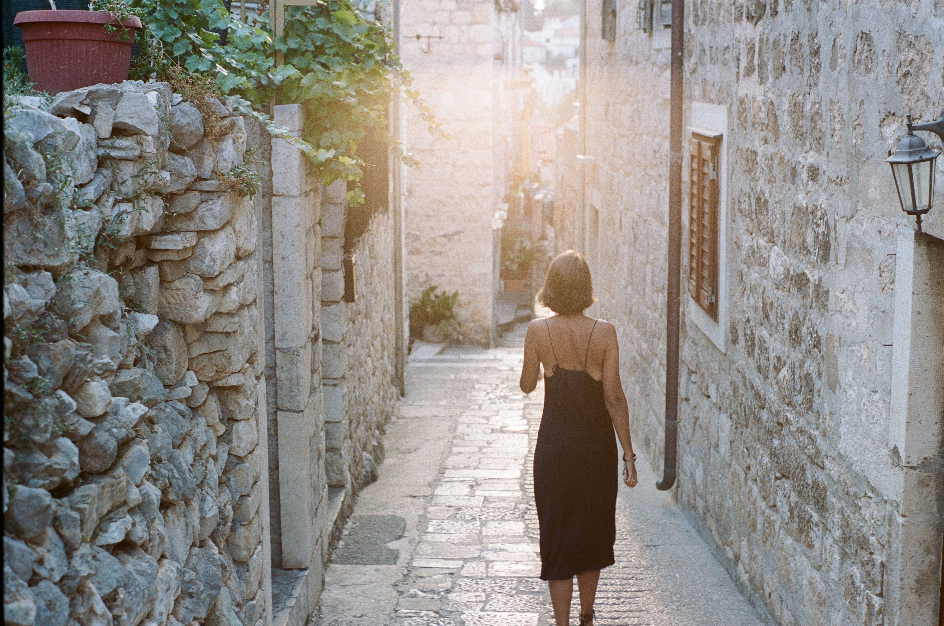 A woman walking down a narrow cobbled street