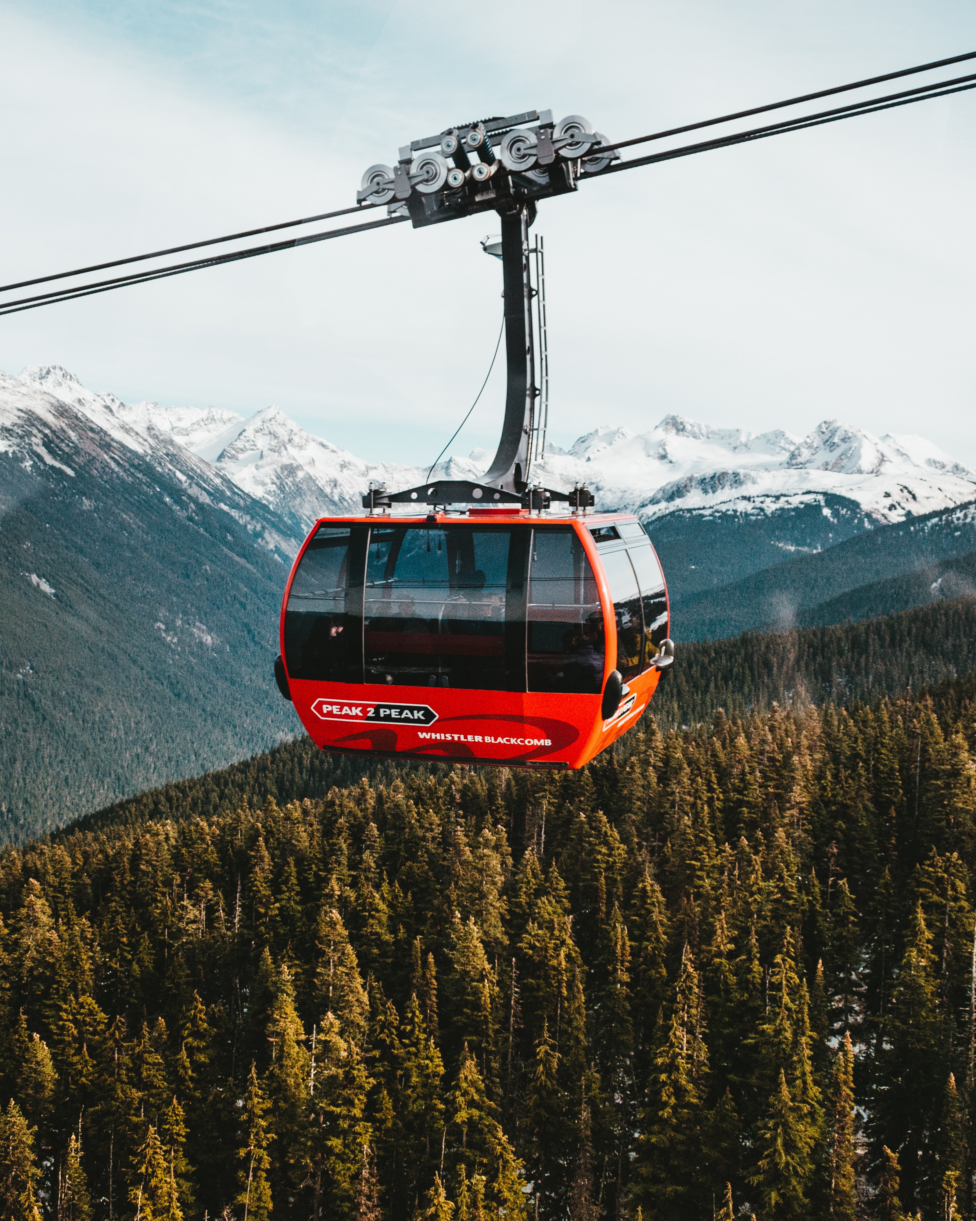 Red and black peak to peak cable car over pine trees in Whistler, Blackcomb