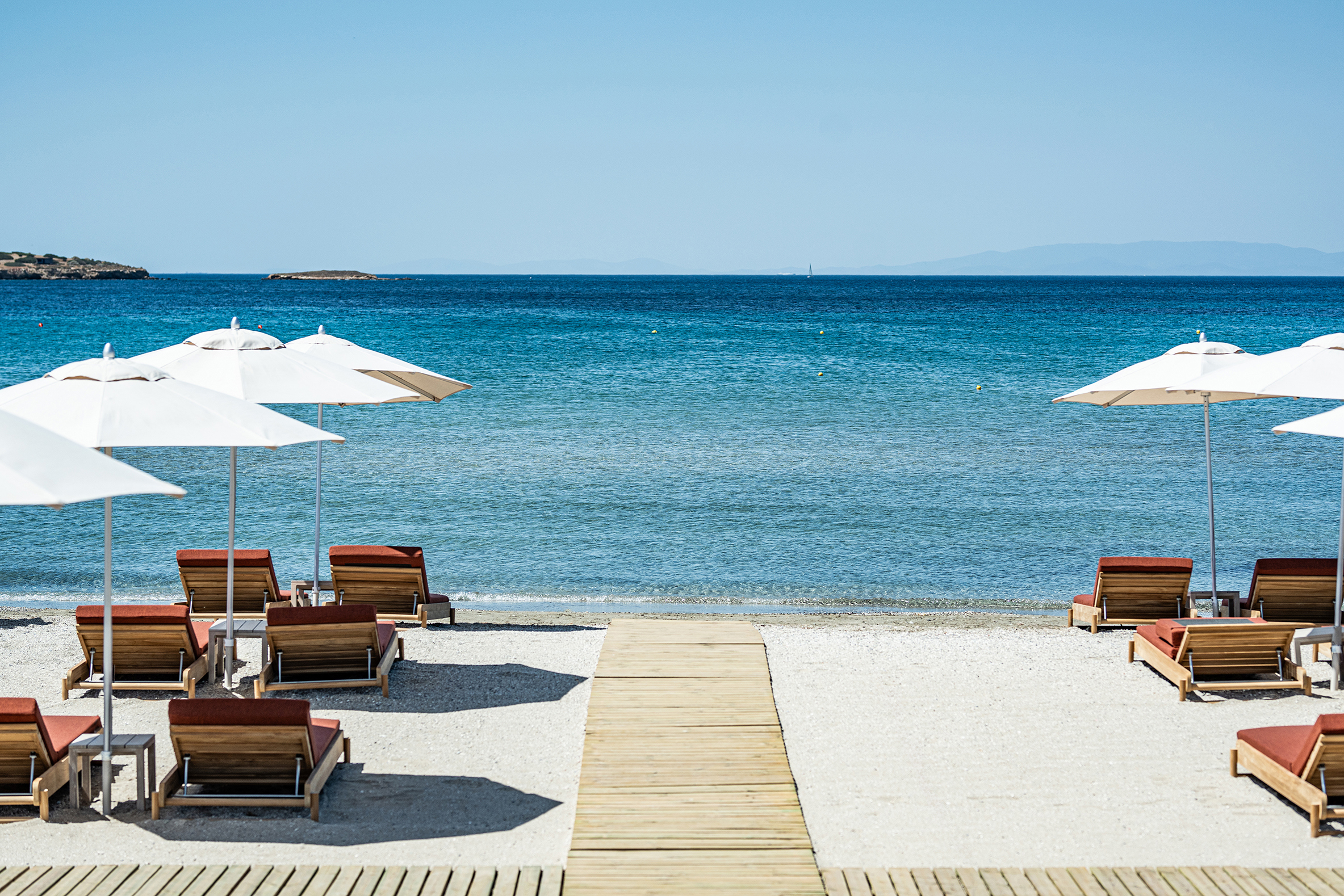 White sand beach with wooden walkway and loungers looking out to sea