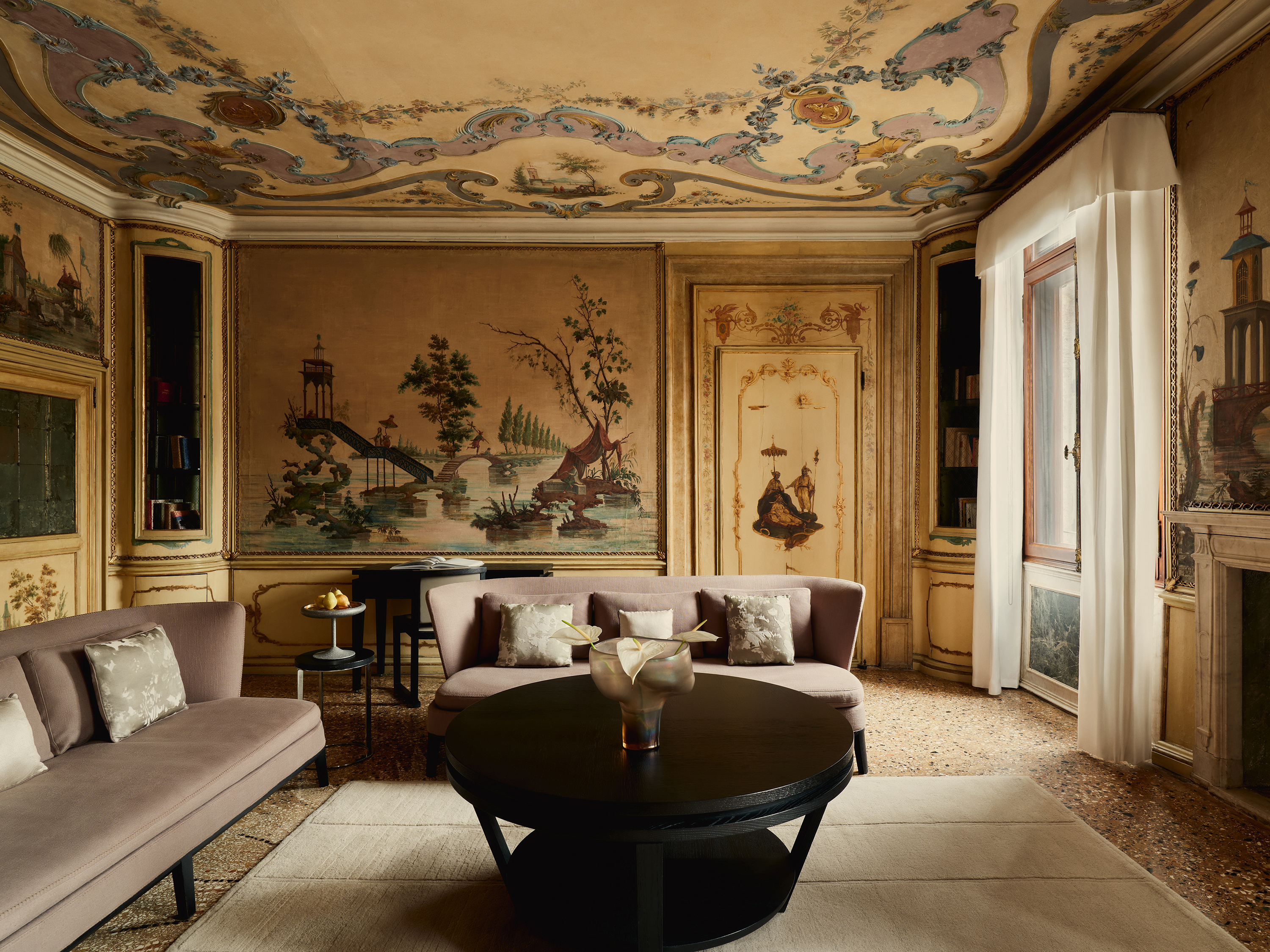 An ornate lounge with painted walls and ceiling, featuring relaxed furniture and baroque details
