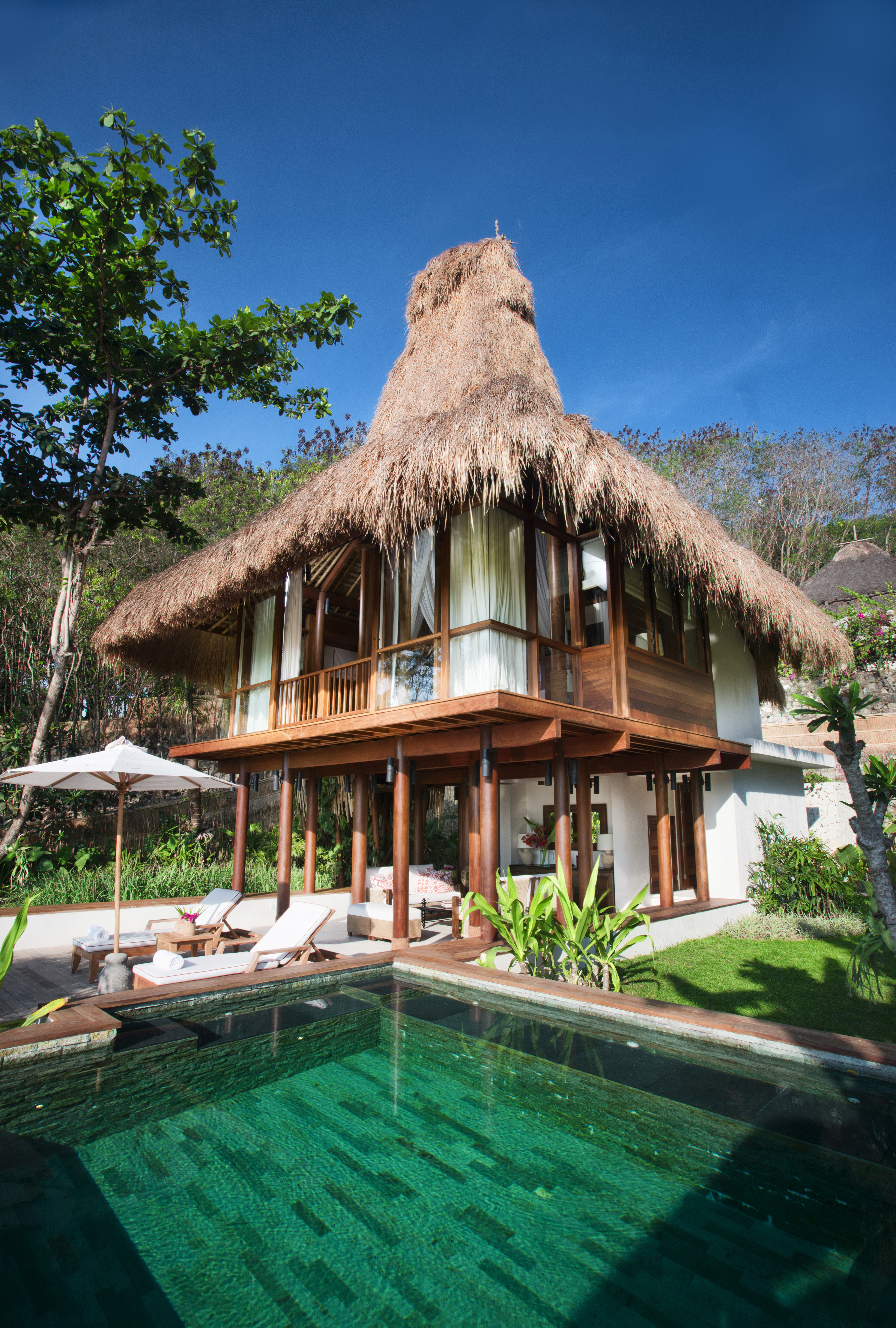 A large wooden-fronted building partly on stilts with a pool and thatched conical roof at Kanatar Sumba House