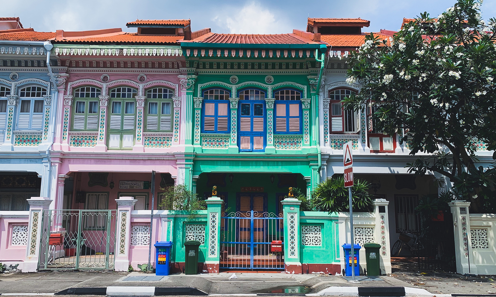 Looking from the street at a row of green and pink houses with traditional patterns